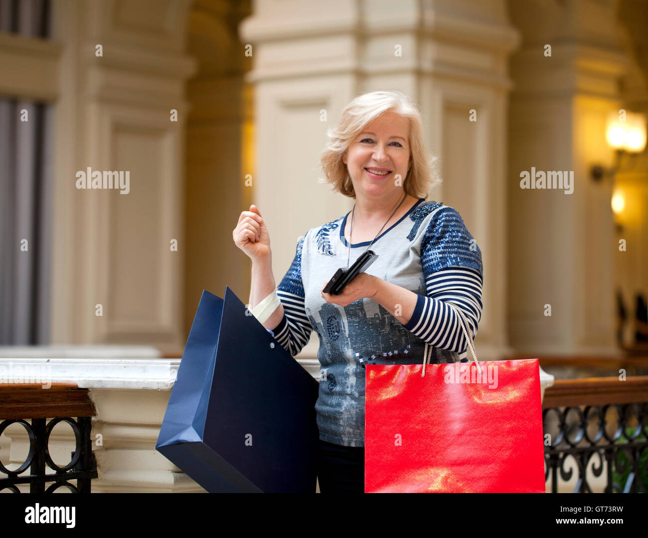 Happy blonde mature woman with shopping bags Banque D'Images