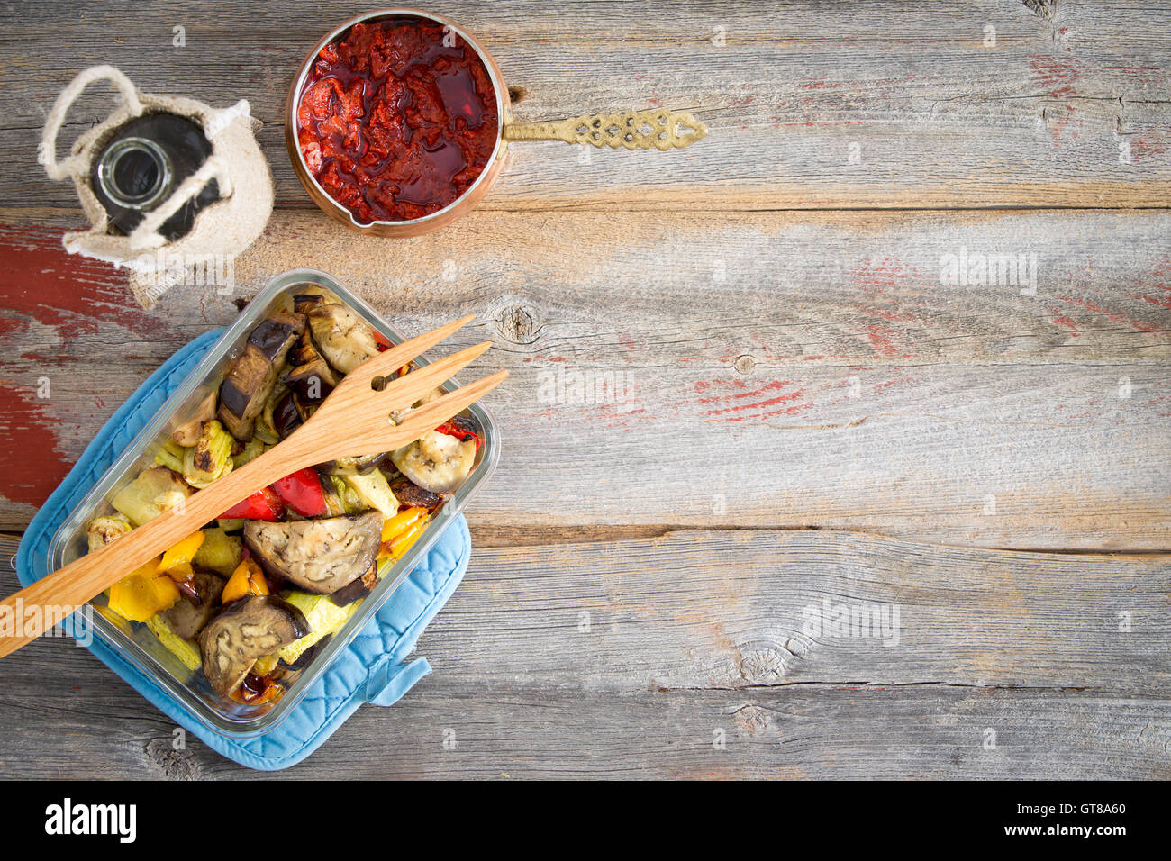 Rôti sain de style turc légumes servi avec une pâte de piment rouge piquant chaud et l'huile d'olive sur une table en bois rustique avec co Banque D'Images
