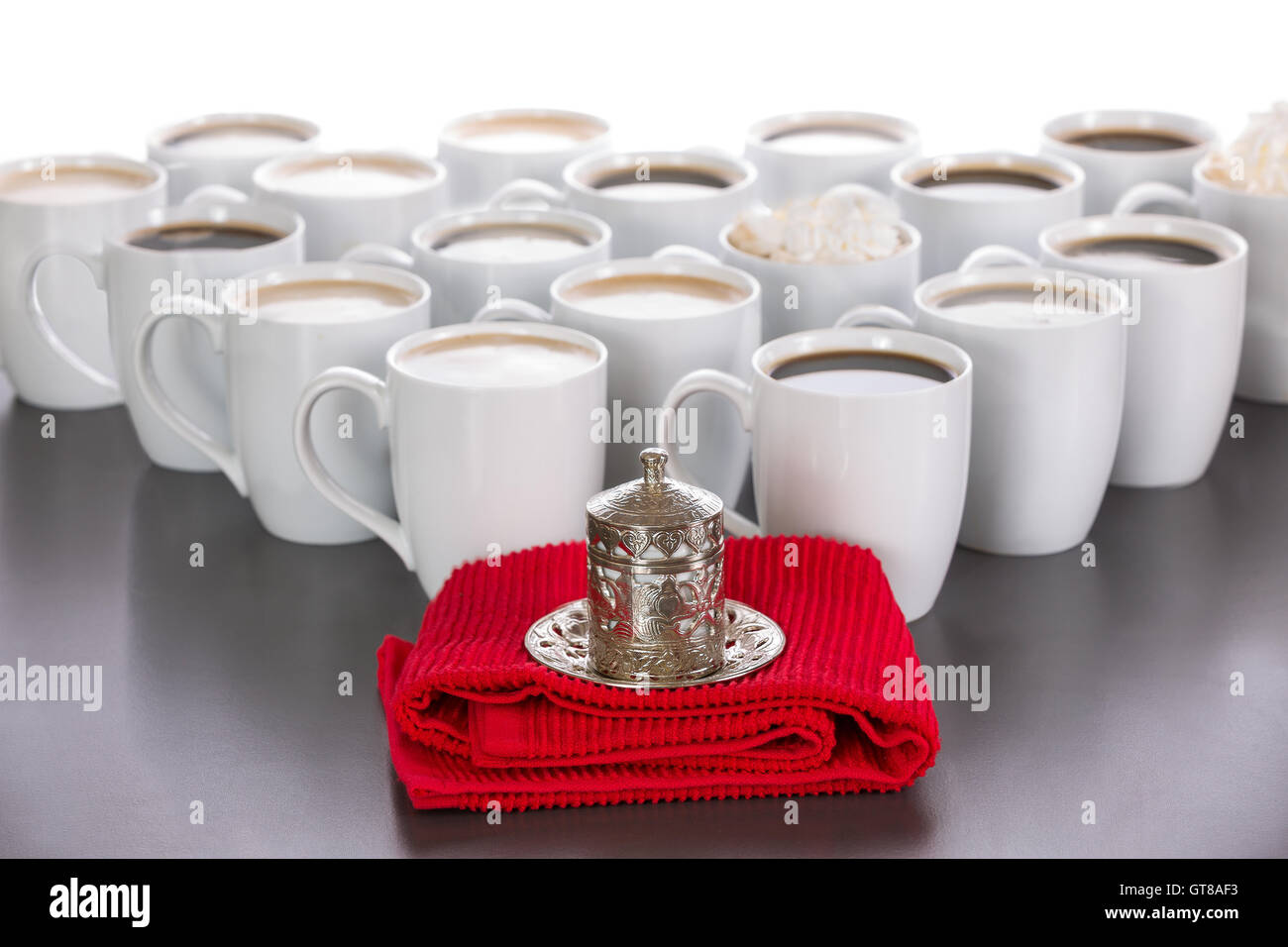 Roi de la notion de café avec une petite tasse de café turc dans une tasse recouverte de métal traditionnel debout sur un tissu rouge en face Banque D'Images