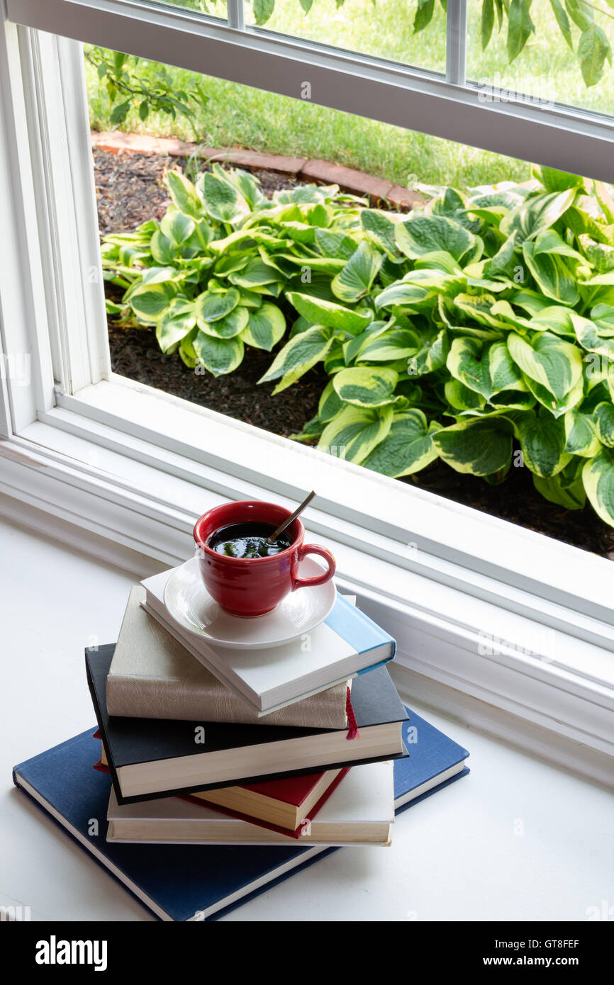 Tasse de café chaud sur le dessus de livres empilés Suivant pour ouvrir la fenêtre de verre pour le temps de lecture Concept. Banque D'Images