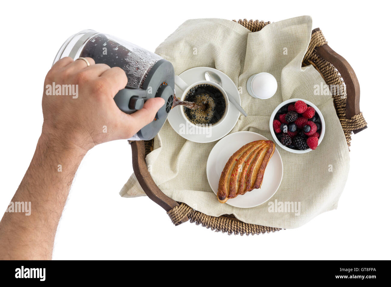 Vue de dessus de la main d'un homme verser lui-même petit-déjeuner frais dans une tasse de café sur un plateau de petit-déjeuner avec les baies fraîches, un pas Banque D'Images