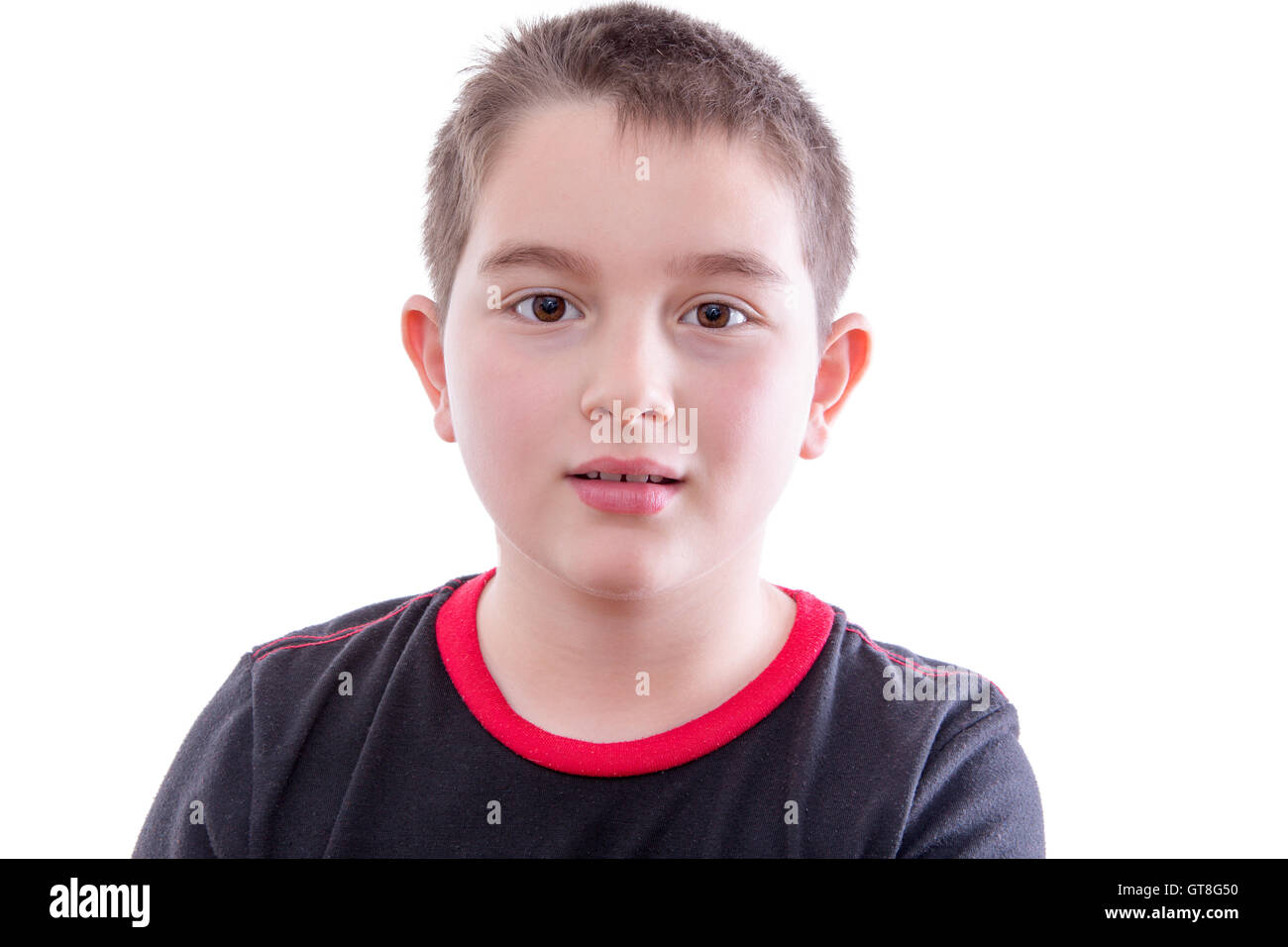 Tête et épaules Close Up Portrait of Young Boy Looking at Camera with Blank Expression in front of White Background Studio Banque D'Images