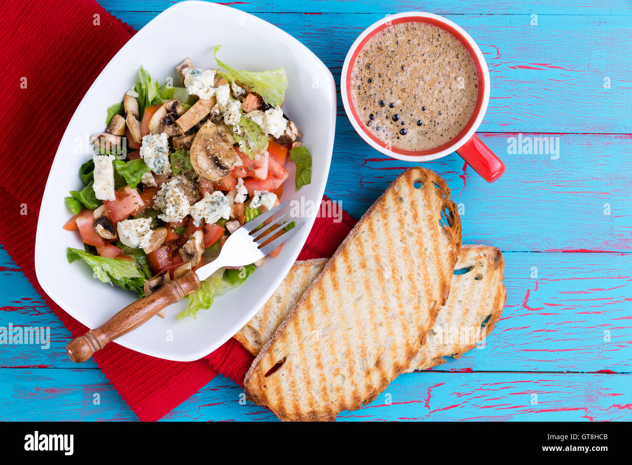 Salade de feta mixte frais sur un plateau servi avec du café espresso mousseux et baguette grillées sur un pique-nique bleu tropical coloré t Banque D'Images