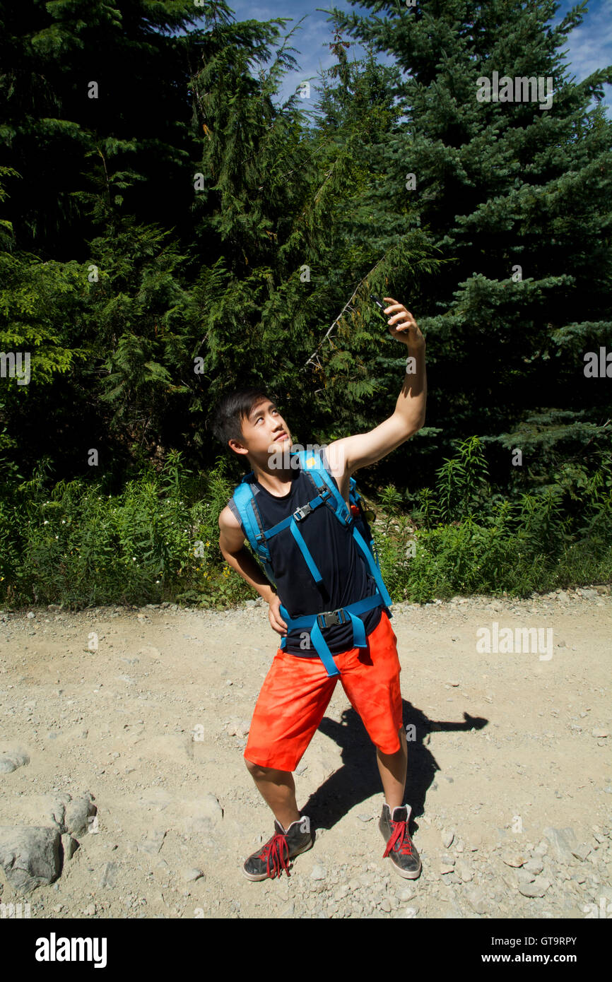 GenY homme prend dans la nature Photo Selfies Smartphone iPhone6 via la technologie Onroute sentier de gravier de Brandywine Meadows Whistler, C.-B. Banque D'Images