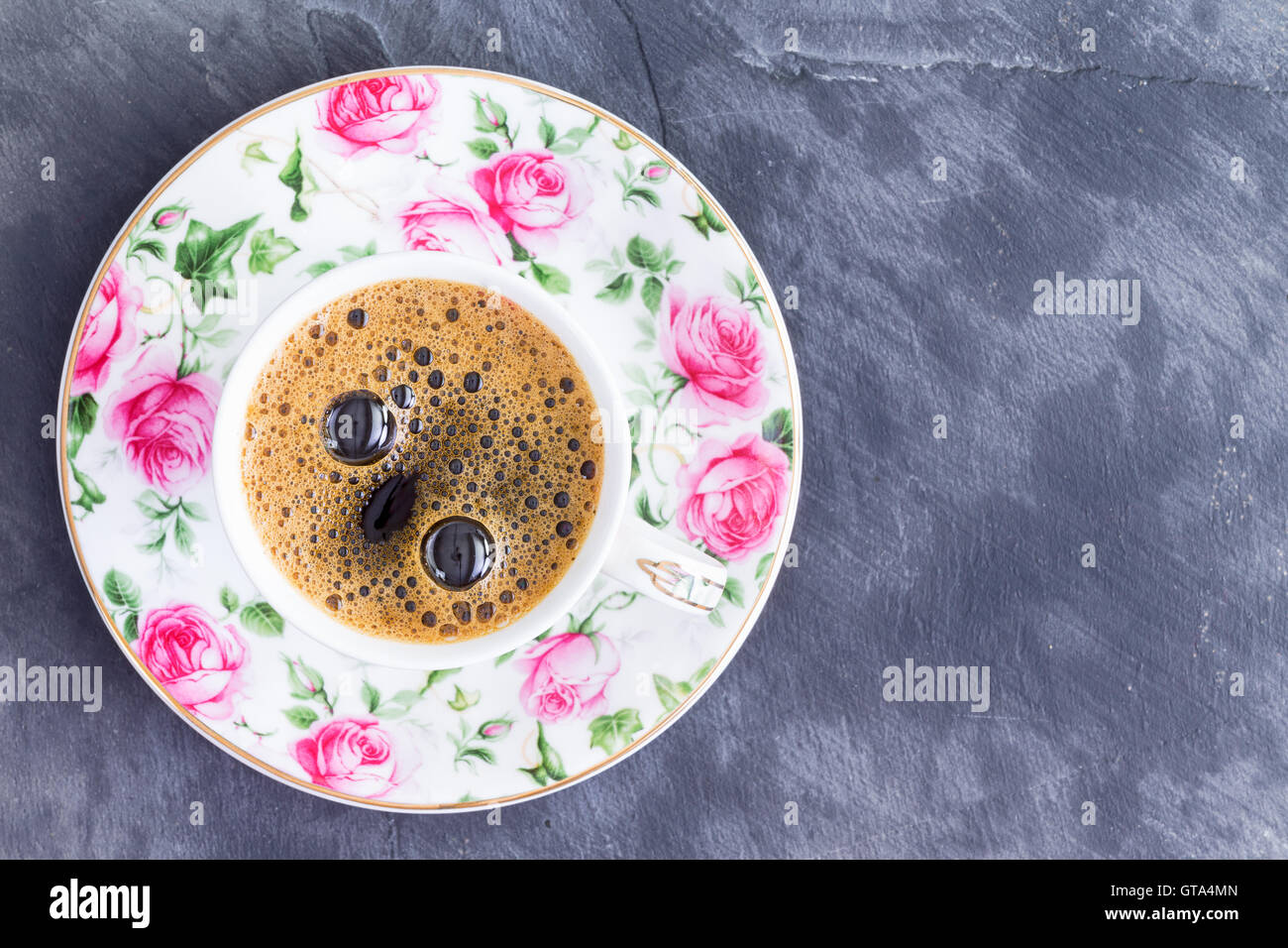 Tasse de café turc noir fort dans une jolie tasse en porcelaine avec des roses rose vue d'en haut sur un fond d'ardoise avec copie s Banque D'Images
