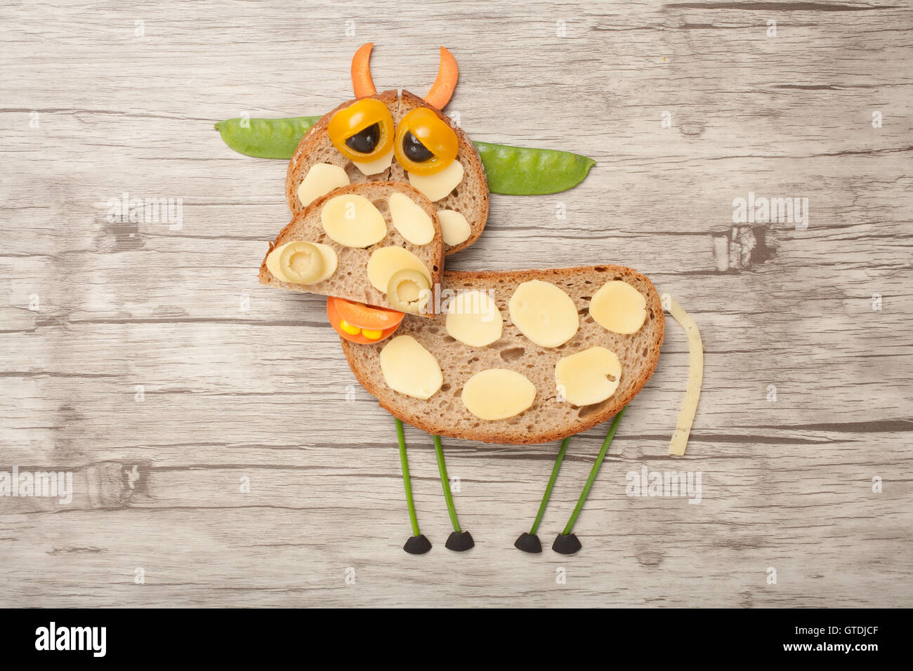 Vache triste fait de pain et de légumes sur fond de bois Banque D'Images