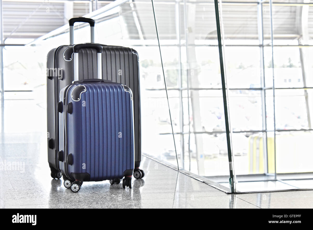 Deux valises de voyage en plastique dans le hall de l'aéroport. Banque D'Images