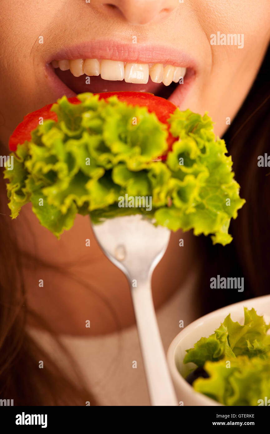 Une saine alimentation - femme mange un bol de salade grecque isolated over white background - végétarien Banque D'Images