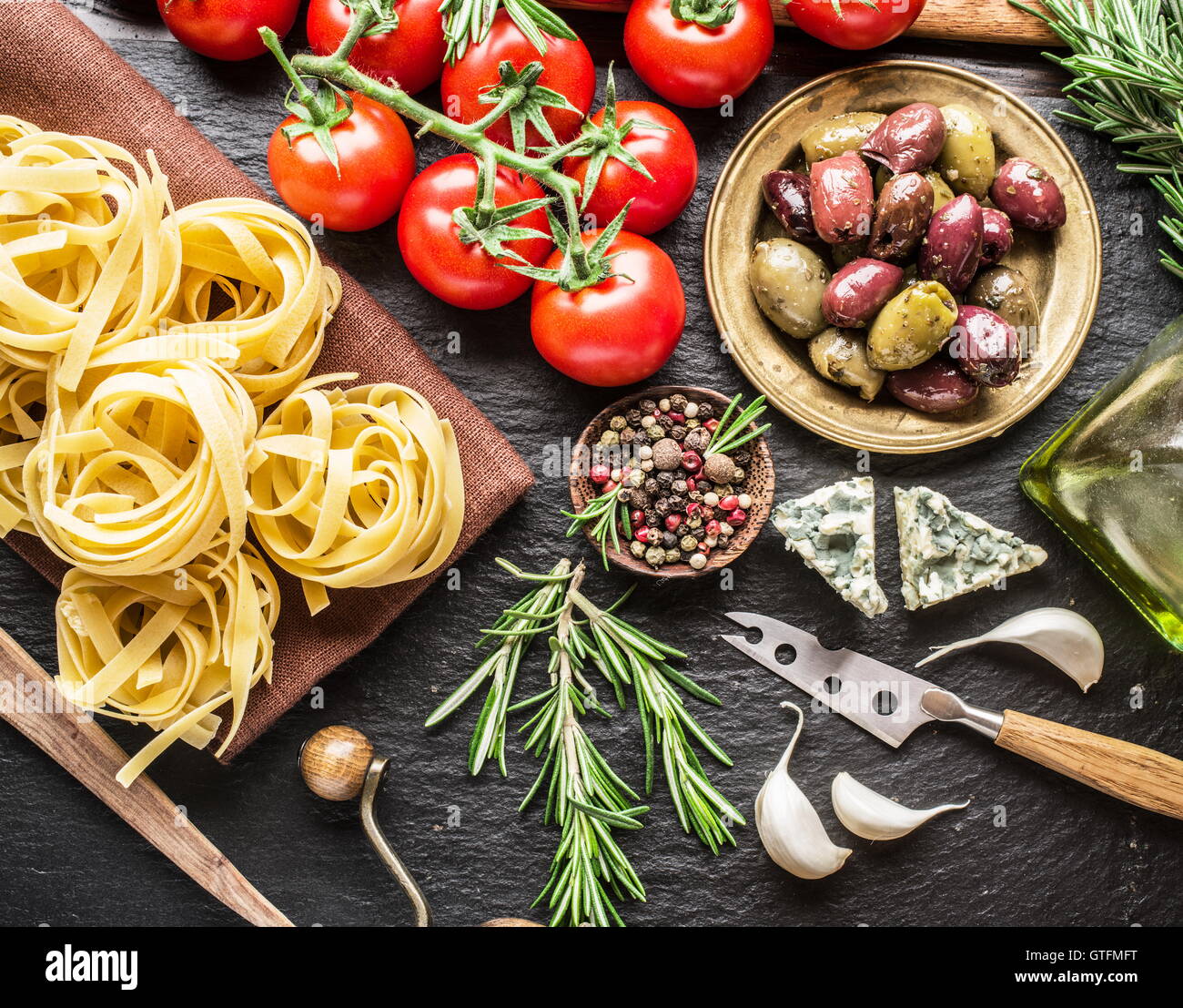 Ingrédients pâtes. Les tomates cerise, les pâtes spaghetti, romarin et d'épices sur une carte de graphite. Banque D'Images