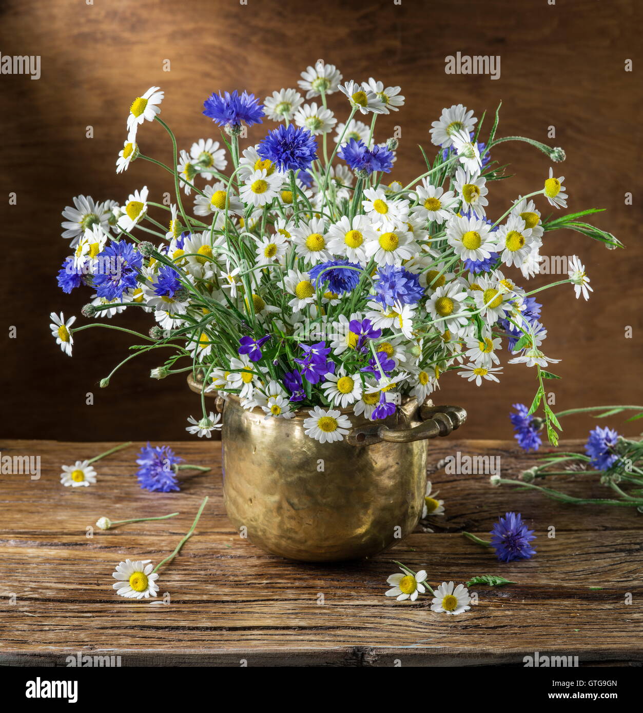 Bouquet de camomille et barbeaux dans le vase sur la table en bois. Banque D'Images