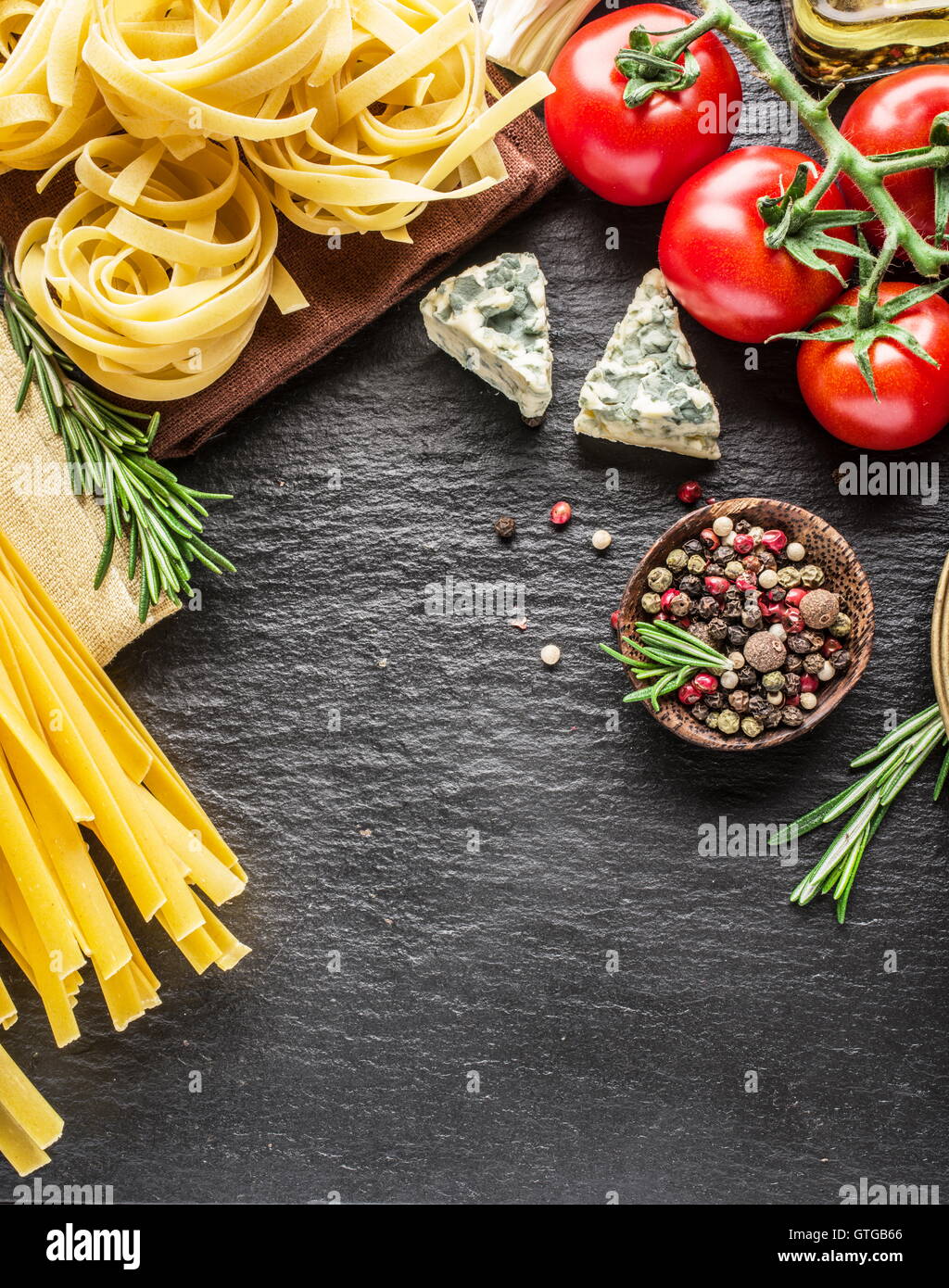 Ingrédients pâtes. Les tomates cerise, les pâtes spaghetti, romarin et d'épices sur une carte de graphite. Banque D'Images