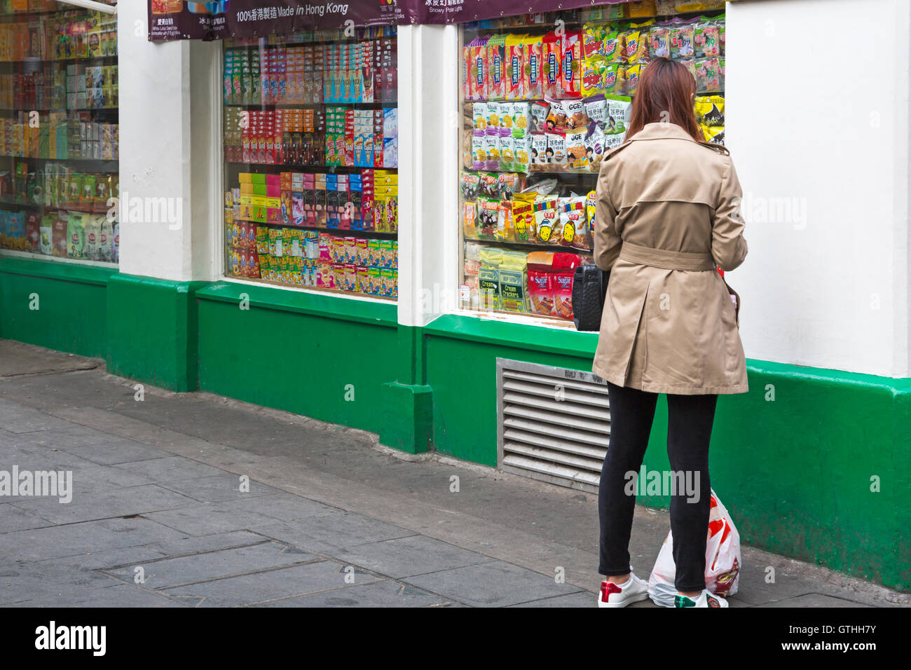 Femme debout à l'extérieur de l'atelier/magasin vendant de la nourriture dans Chinatown, Soho, Londres en septembre Banque D'Images