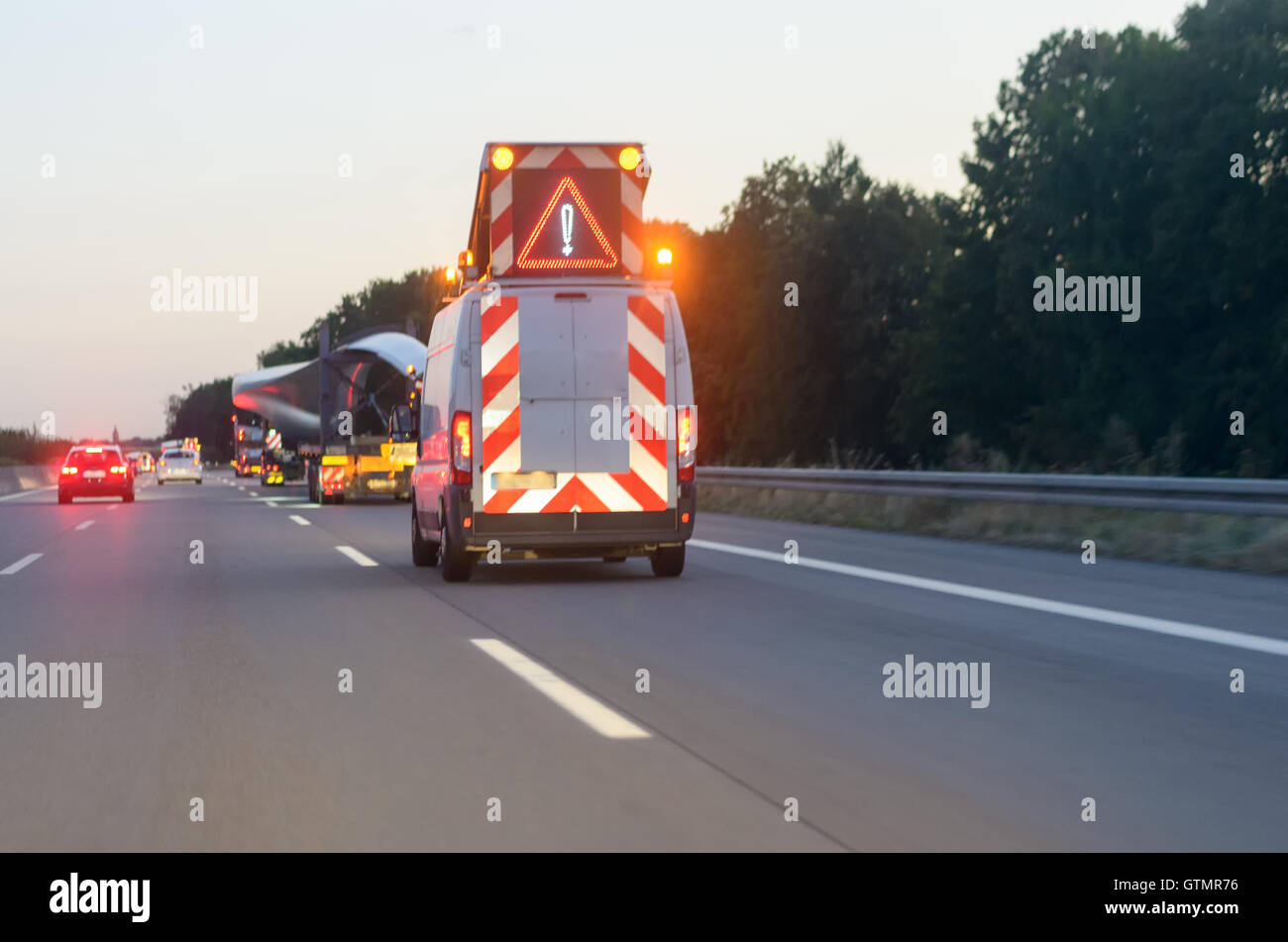 Véhicule d'avertissement pour un convoi sur une route, conduisant le long derrière les camions de transport avec un triangle de prudence et flash Banque D'Images