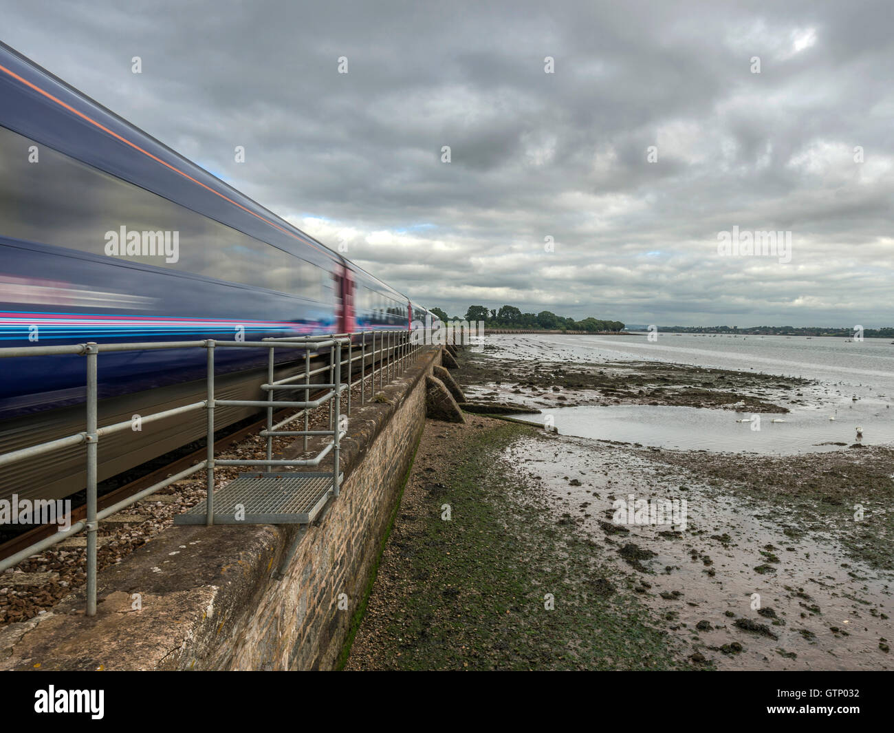 Représentant un paysage pittoresque Riviera First Great Western Railway line le long de la rivière Exe à Powderham, avec train qui passe. Banque D'Images