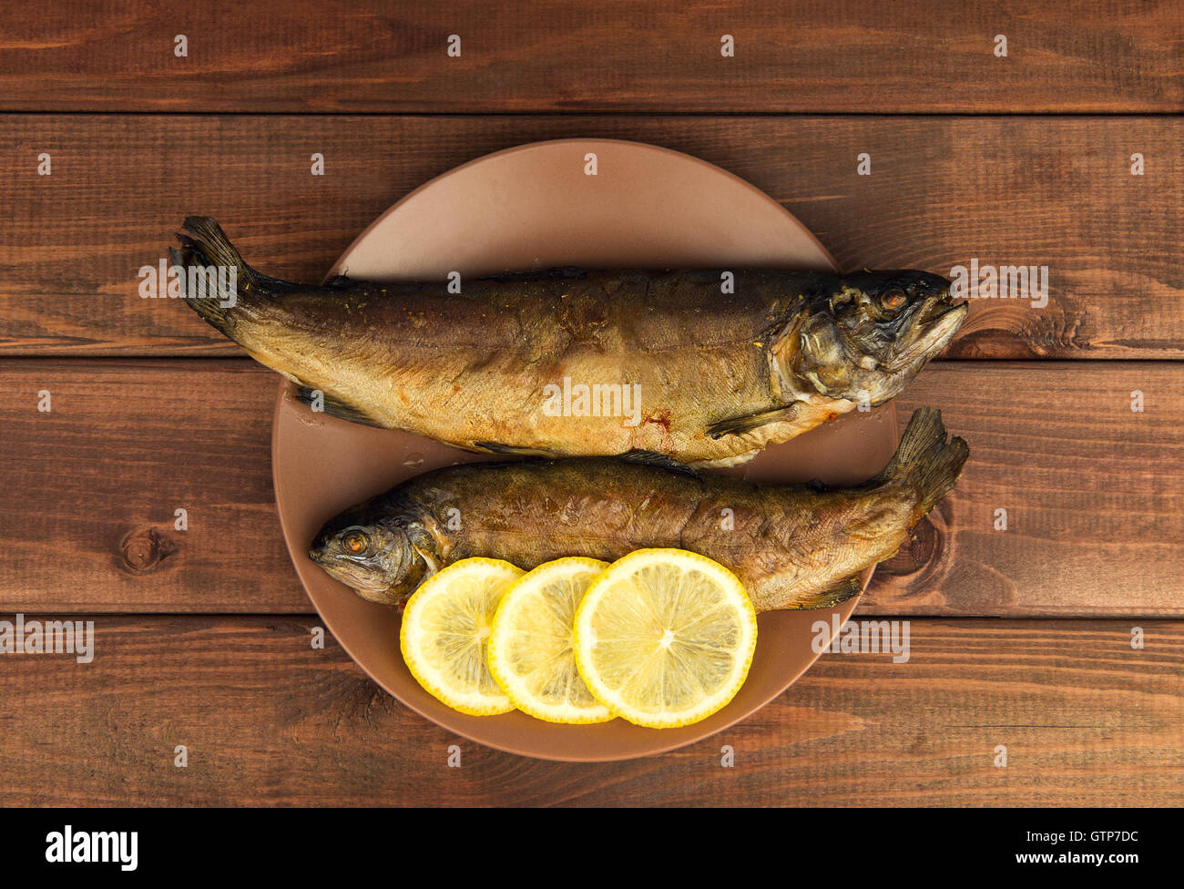 Sur la table en bois est une plaque avec deux truite poisson au four avec du citron Banque D'Images