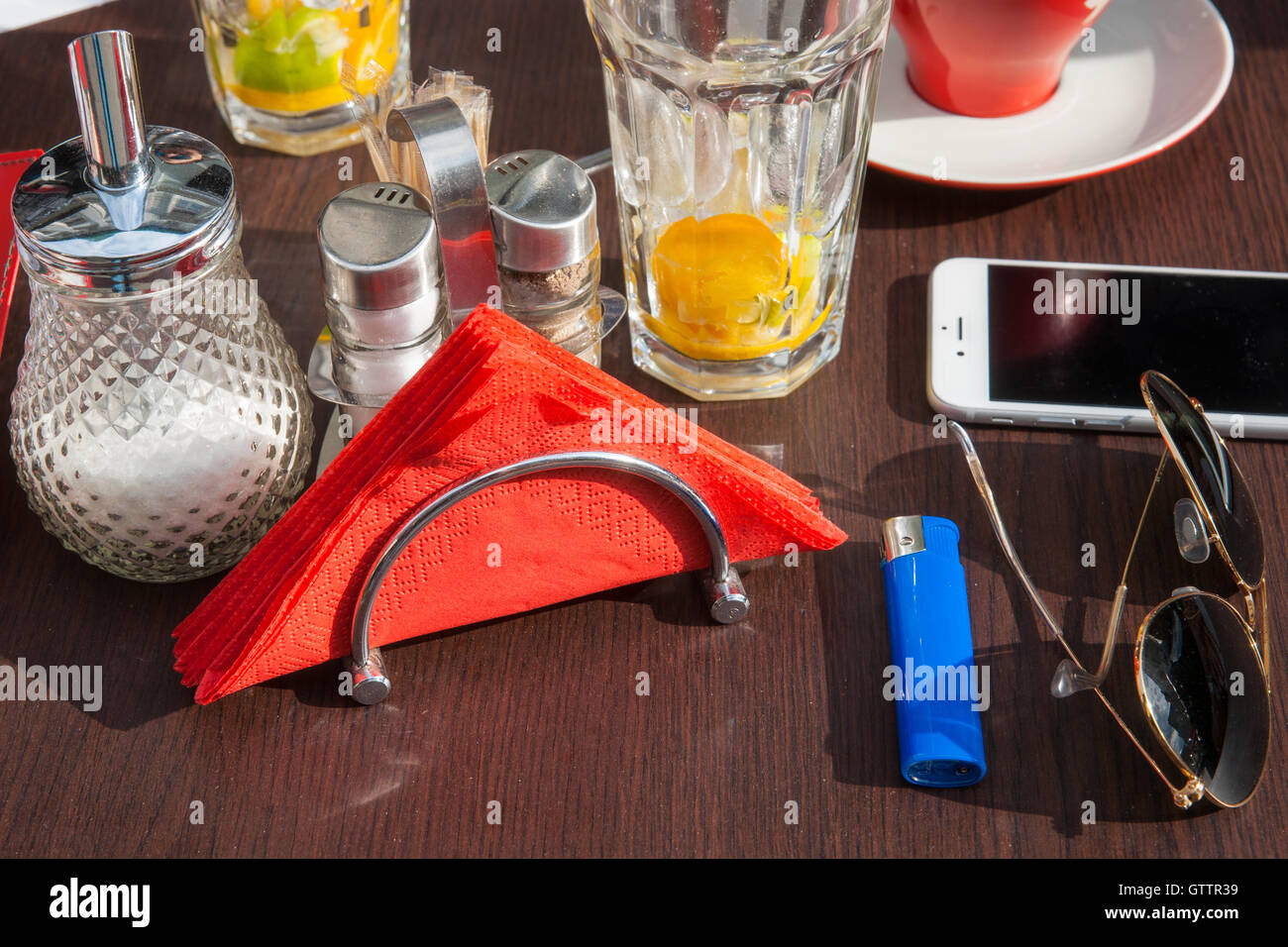 Street Café table. Verres vides, rouge serviettes, bol de sucre, sel, poivre, lunettes, téléphone portable, allume-cigare. Banque D'Images