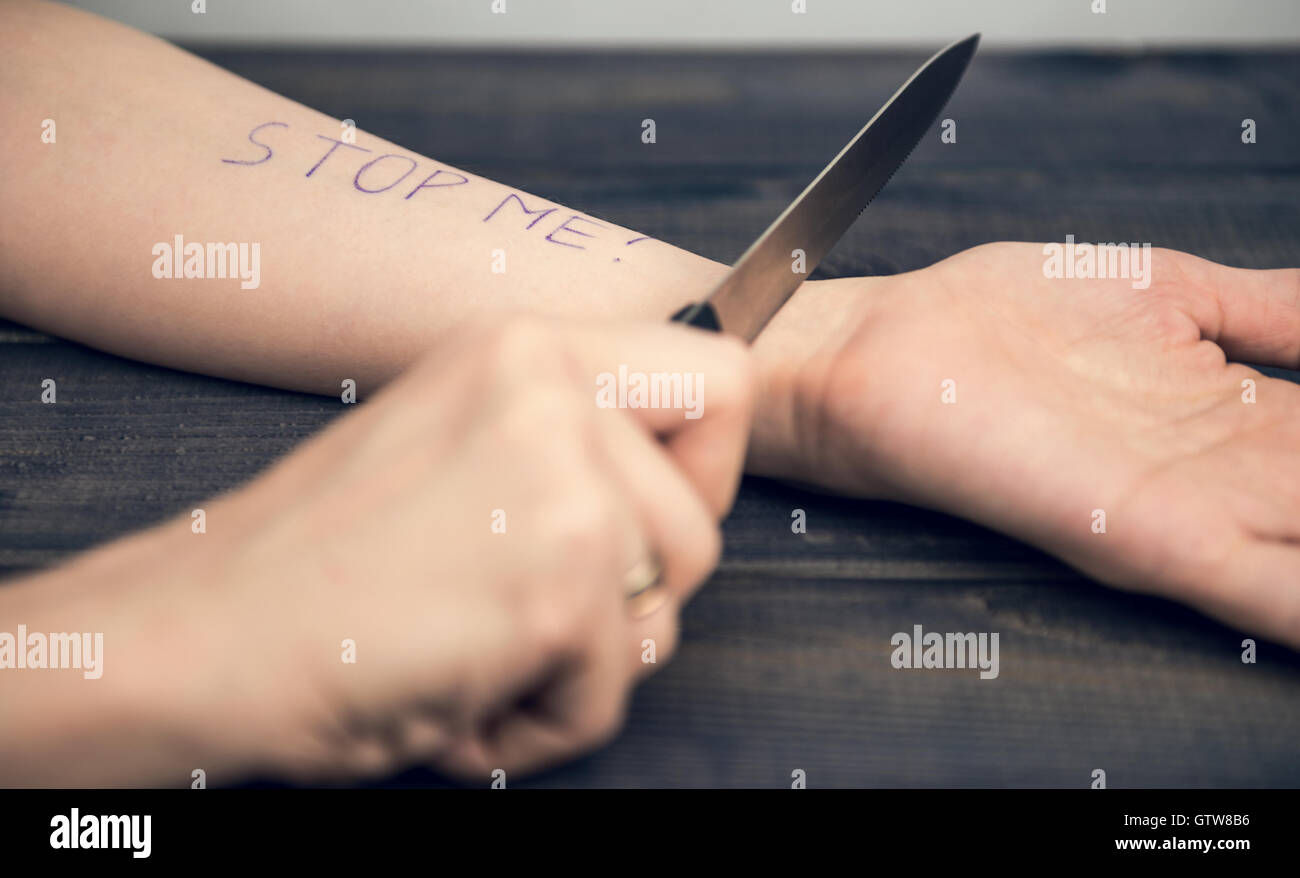 Fille dans une tentative de suicide, posa une main sur le bureau en bois et tenant un couteau de ses veines, elle veut couper les veines Banque D'Images