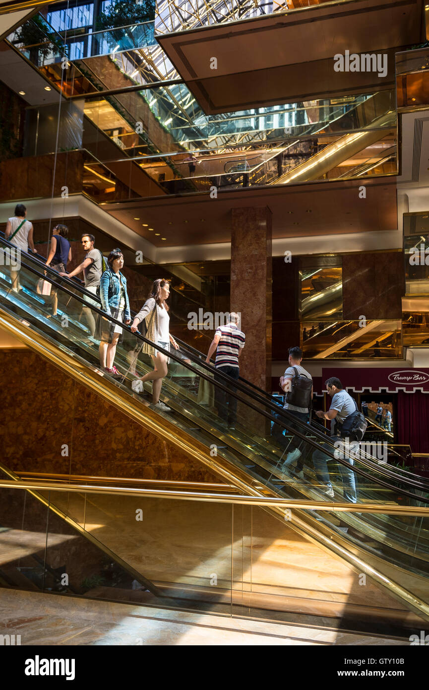 NEW YORK - 3 septembre 2016 : les visiteurs monter les escaliers mécaniques en laiton en miroir dans l'atrium de marbre rose la Trump Tower. Banque D'Images