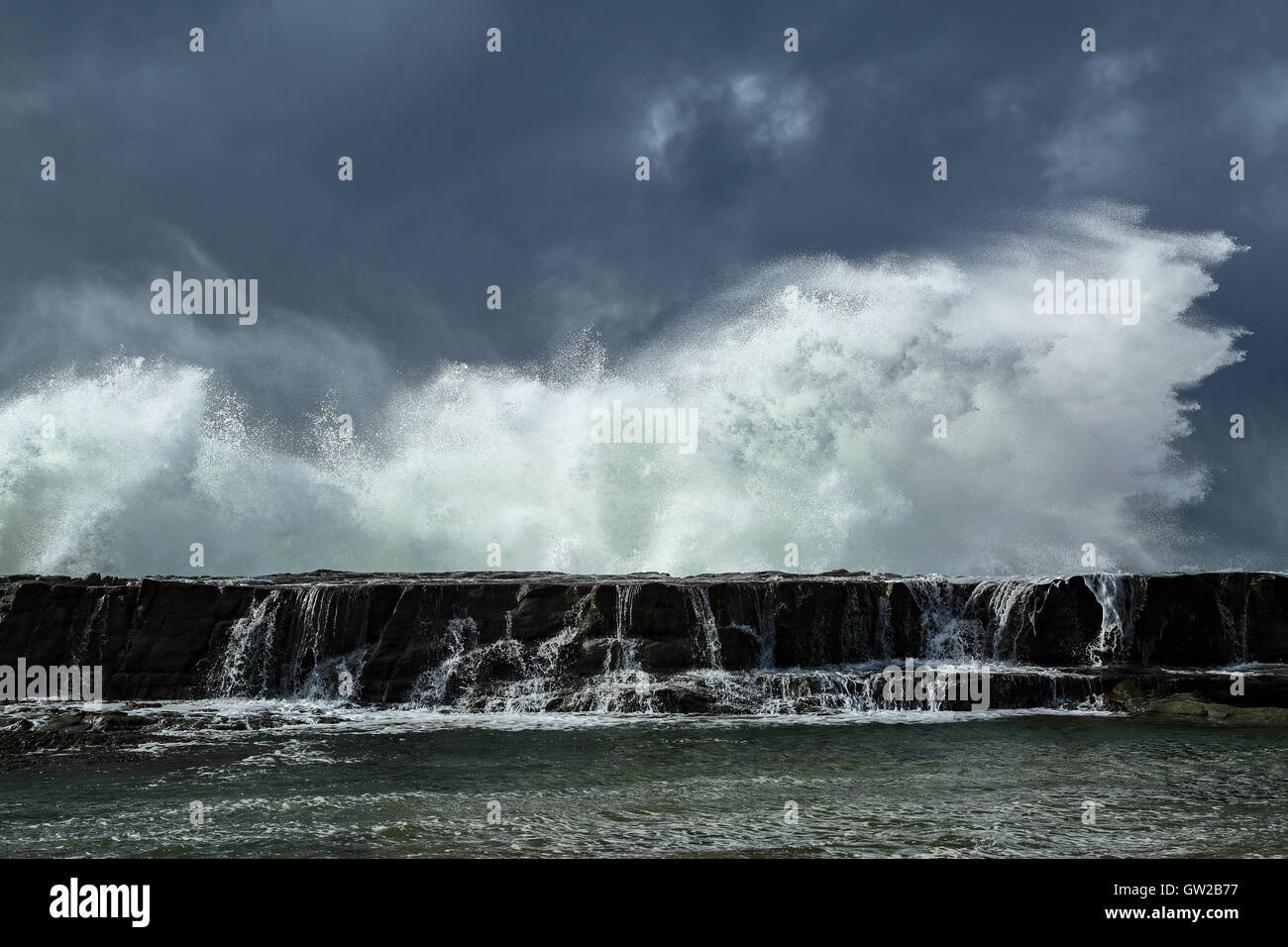 Une tempête hivernale whips de grandes et puissantes vagues qui s'écraser sur une plage, sous un ciel lourd. Banque D'Images