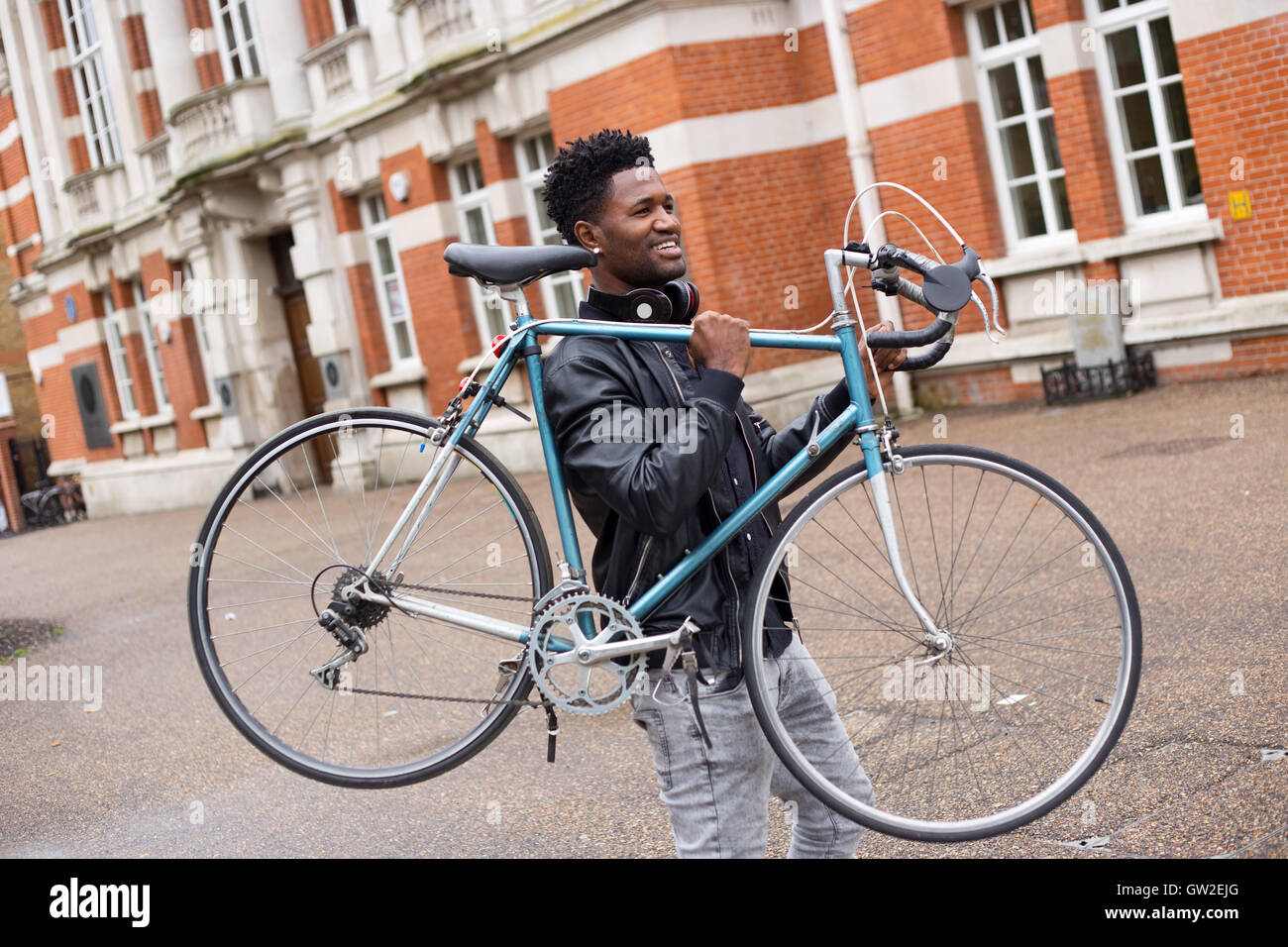 Jeune homme portant son vélo Banque D'Images