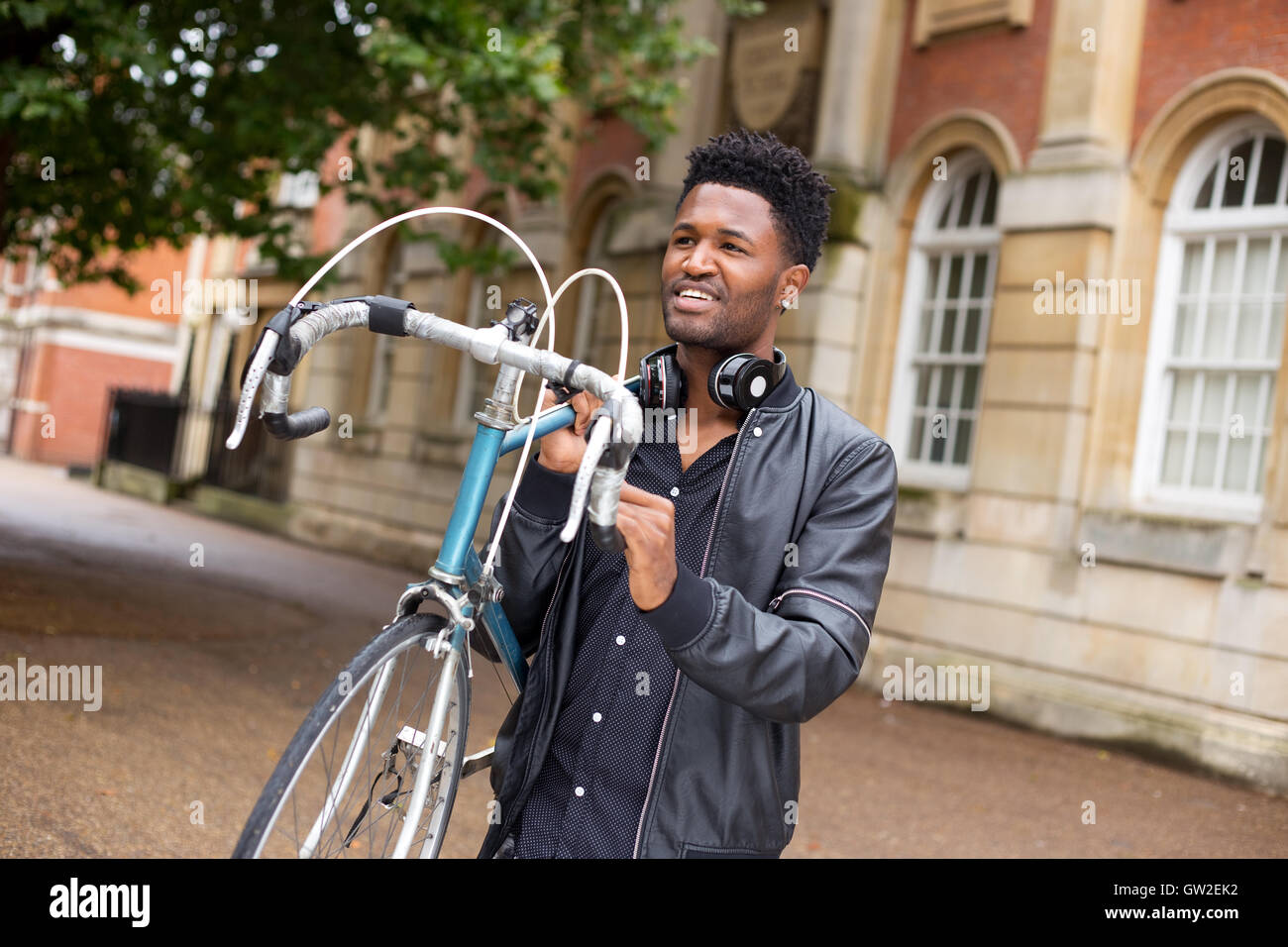 Jeune homme portant son vélo dans la rue Banque D'Images