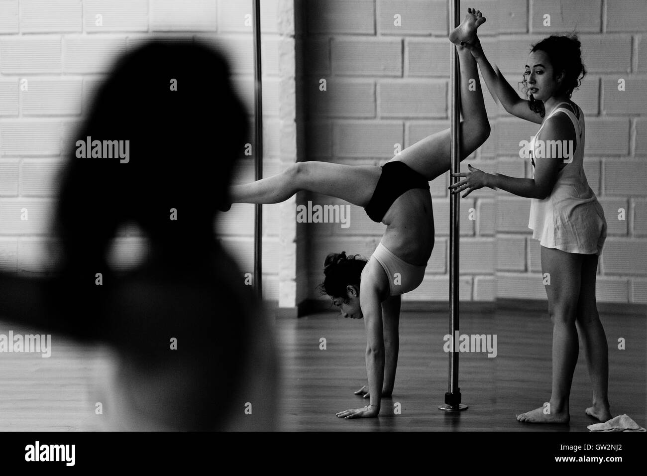 Carolina Echavarria aide Valeria Aboultaif pendant qu'elle effectue au cours d'une session de formation pole dance dans le monde universitaire Pin Up à Medellín, Colombie. Banque D'Images