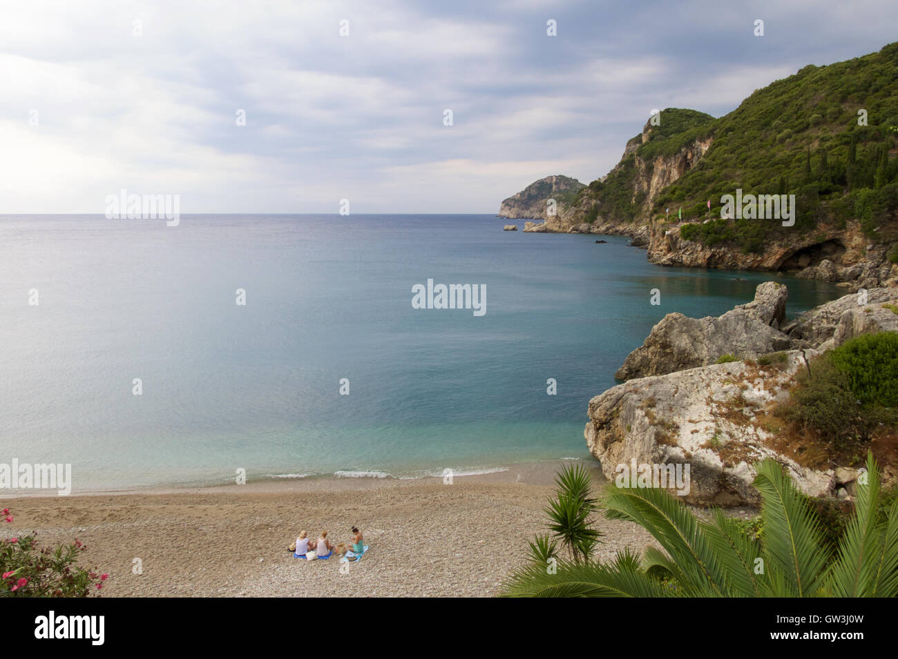 Trois femmes assis sur une plage tranquille en admirant la vue magnifique sur la mer à Liapades Beach, Corfou, Grèce. Banque D'Images