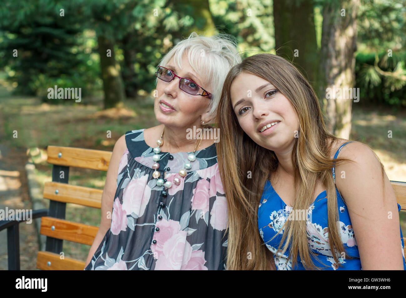 Deux femmes de générations différentes assis sur un banc dans l'été Banque D'Images