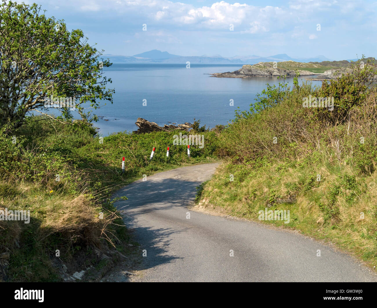 Une piste sinueuse route sur l'île de Colonsay avec vue sur la mer à l'île de Mull dans les Hébrides intérieures, Ecosse, Royaume-Uni. Banque D'Images