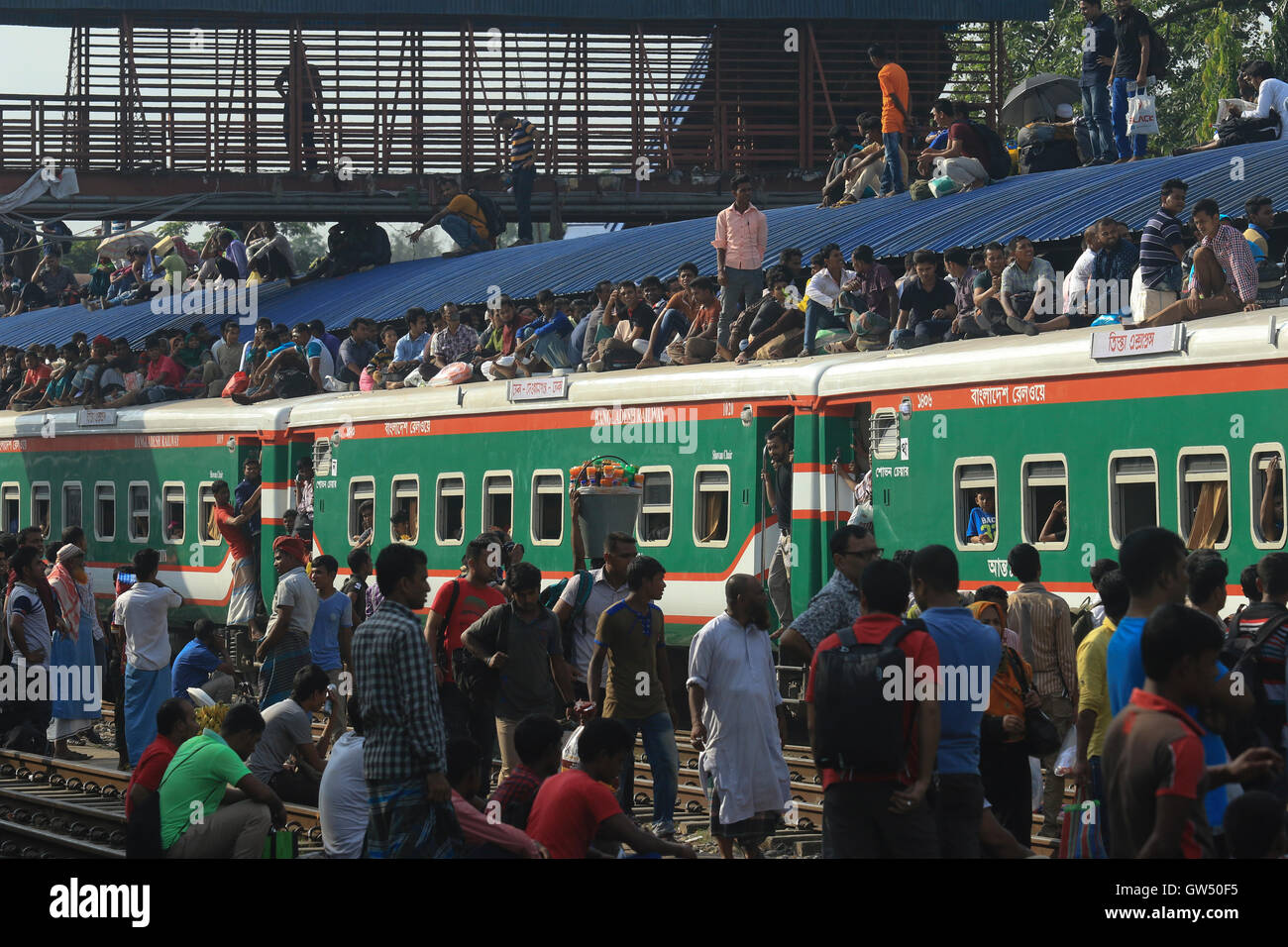 Les personnes à faible revenu à surcharger le toit d'un train à la gare de l''aéroport de Dacca comme ils voyage, au péril de leur vie, à leur Banque D'Images