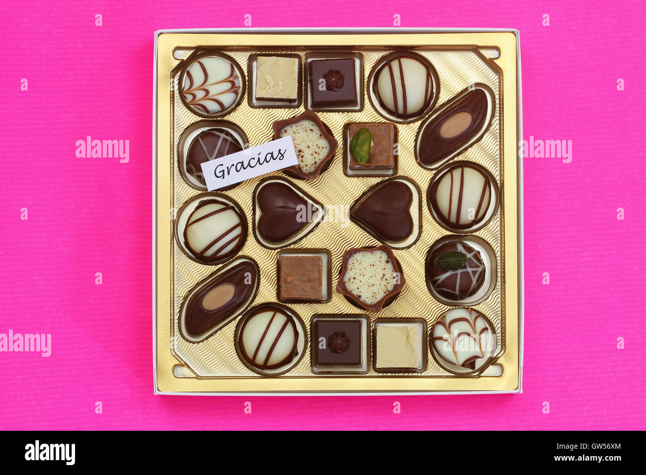 Gracias (ce qui signifie merci en espagnol) avec boîte de chocolats assortis sur fond rose Banque D'Images