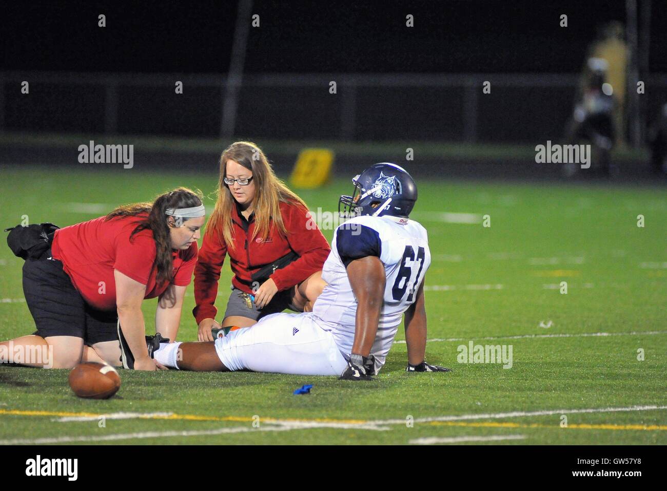 Un joueur de football de l'école secondaire est traité pour une blessure tout en bas sur la pelouse. USA. Banque D'Images