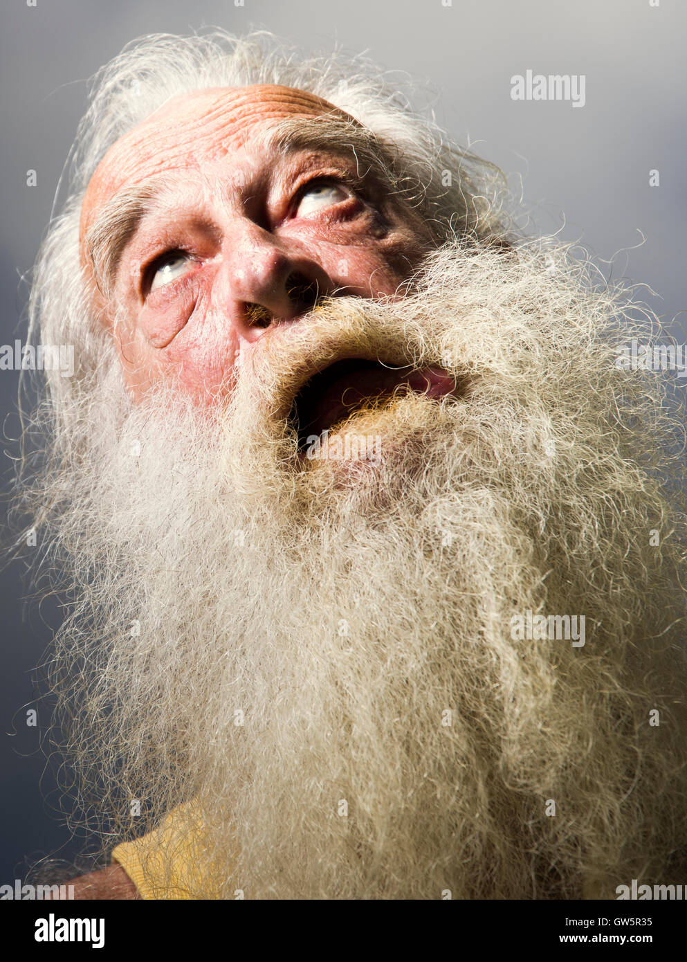 Vieil homme à barbe blanche à la bouche ouverte vers le ciel. Banque D'Images