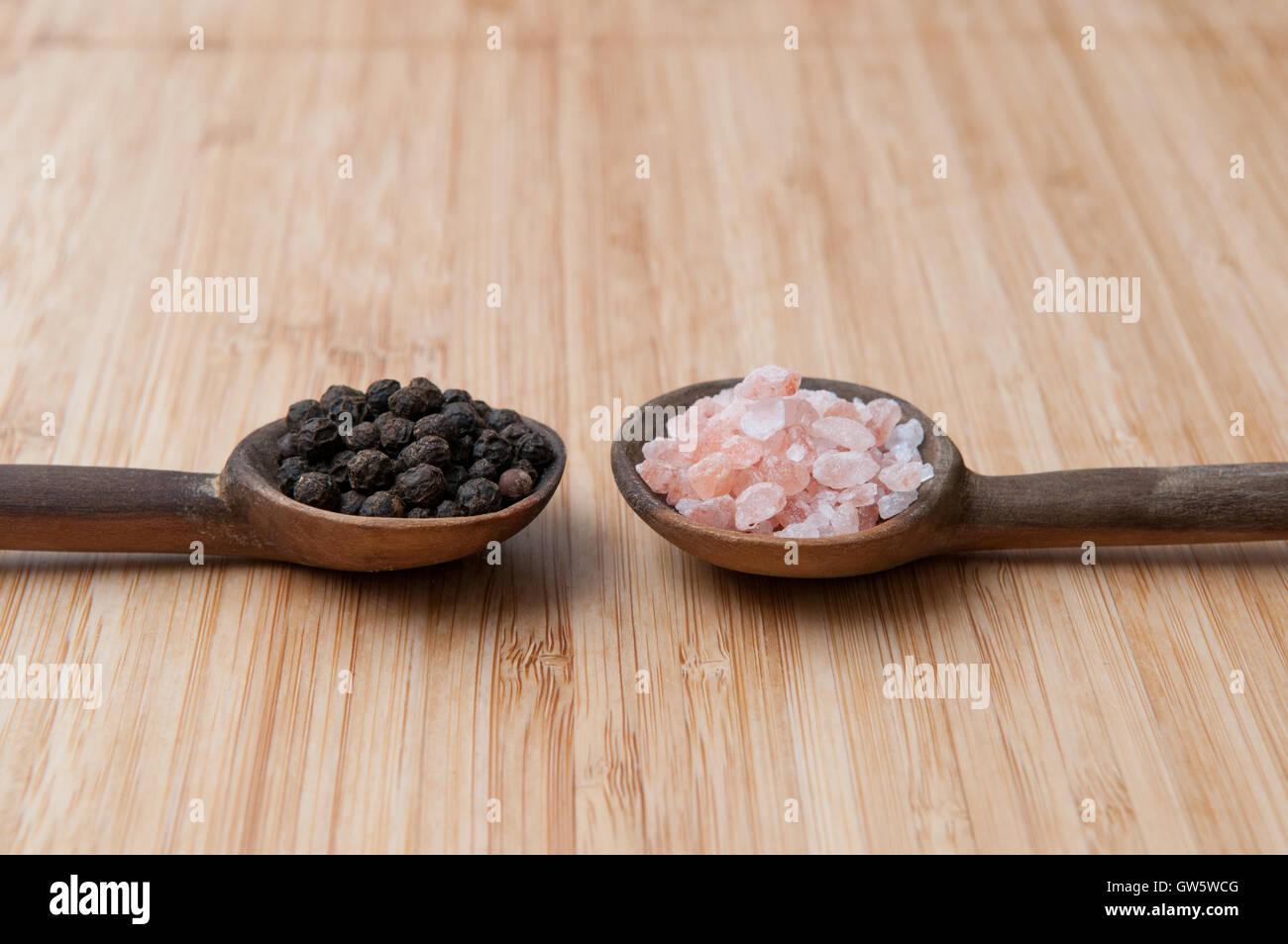 Assaisonnements Sel et poivre de poivre en grains et le sel gemme sur les cuillères en bois Banque D'Images