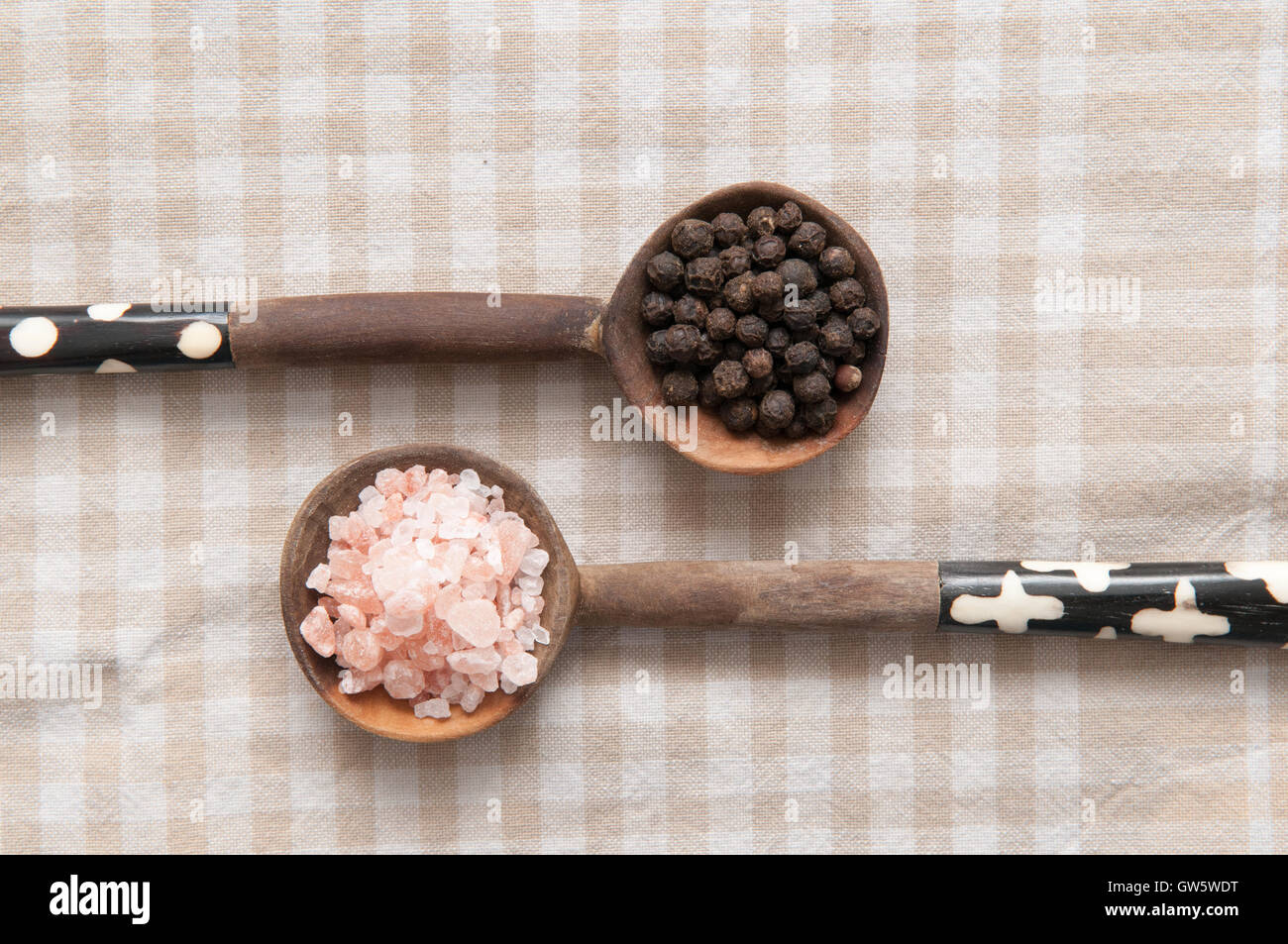 Assaisonnements Sel et poivre de poivre en grains et le sel gemme sur les cuillères en bois Banque D'Images