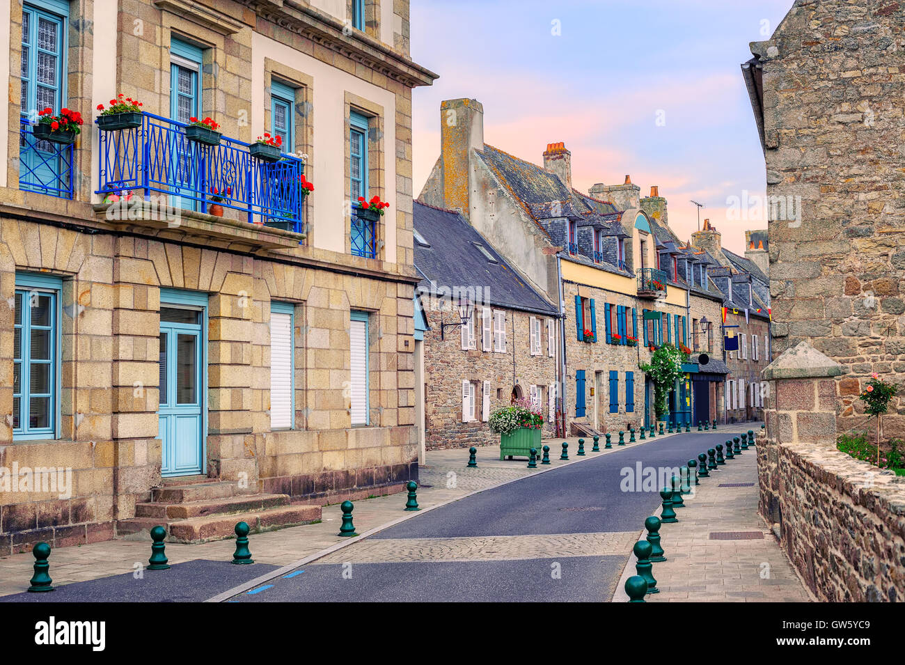 Maisons en pierre traditionnelle française avec blue fenêtres décorées de fleurs rouges à Roscoff, Bretagne, France Banque D'Images
