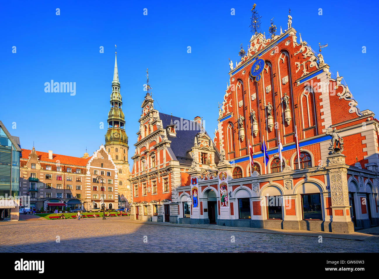 La place de l'Hôtel de ville avec la Maison des Têtes Noires et église Saint Pierre dans la vieille ville de Riga en Lettonie, la lumière au coucher du soleil Banque D'Images