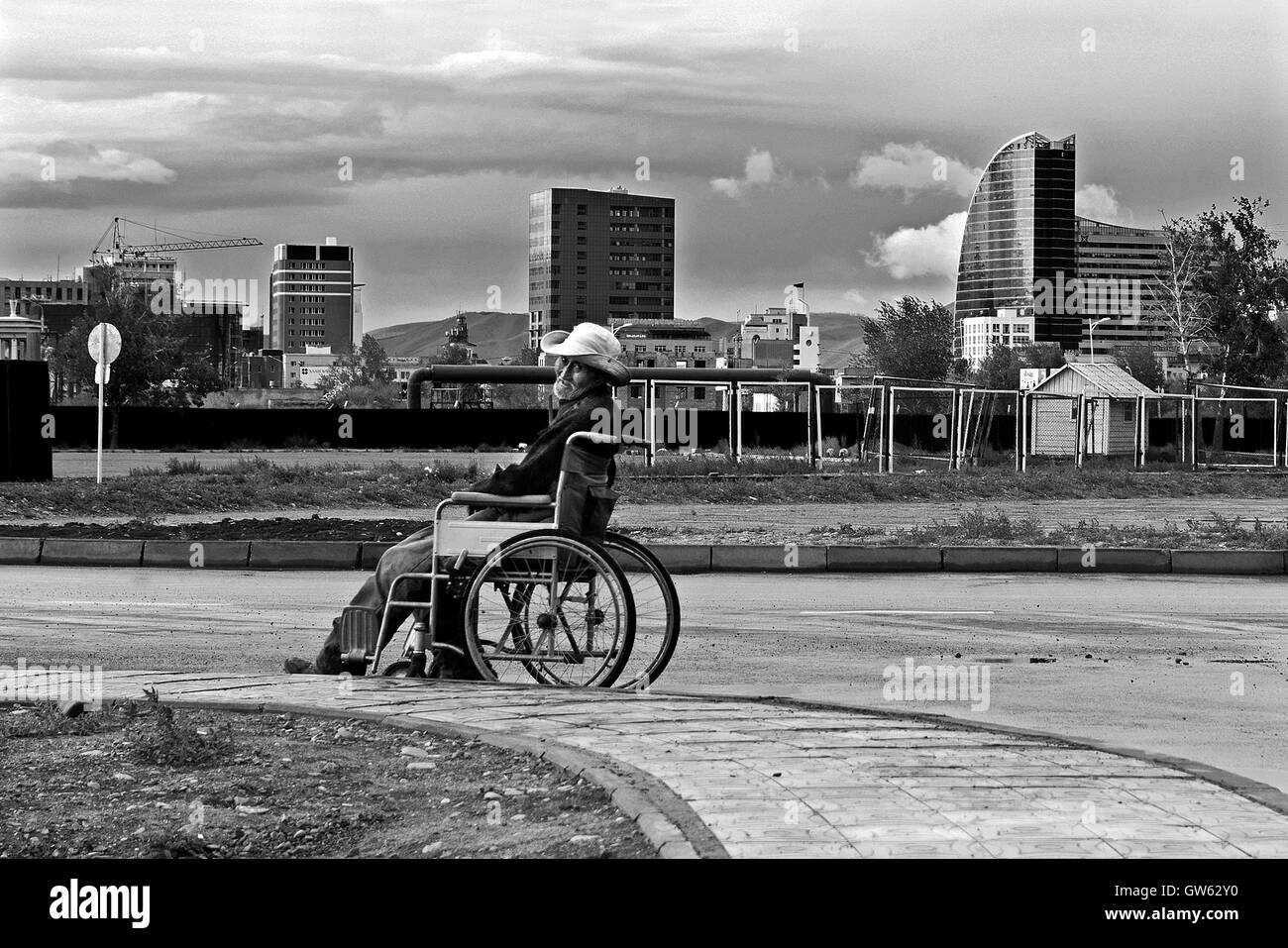 Vieil homme en fauteuil roulant se déplace dans une allée d'un parc sur la banlieue d'Oulan Bator Banque D'Images