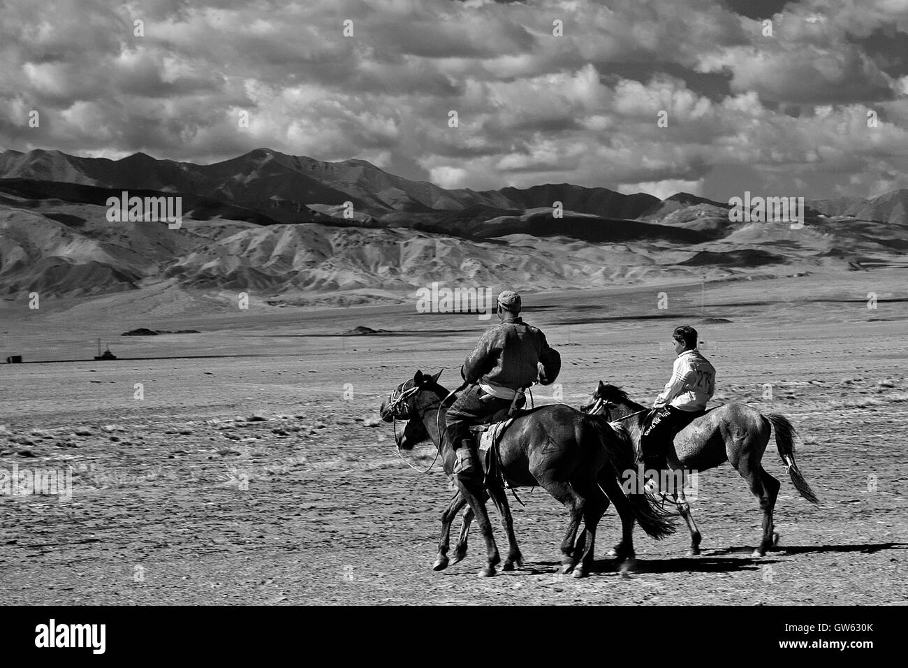 Père et fils à cheval retour à la maison, après la course de chevaux, partie de l'Naddam Festival, dans la région des montagnes de l'Altai, Mongolie Banque D'Images