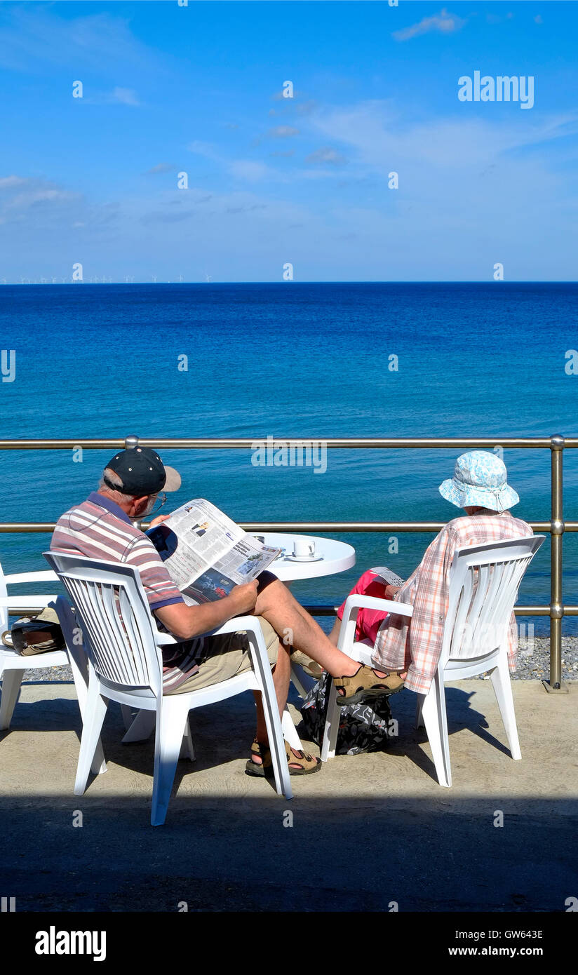 couple senior assis sur la promenade à sheringham, nord de norfolk, angleterre Banque D'Images