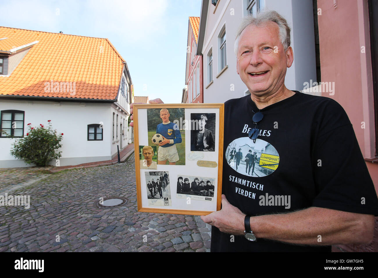 Verden, Allemagne. Sep 9, 2016. Harry Schwertner, co-fondateur de The Beatles groupe de réguliers à Verden, pose avec un cadre photo avec des autographes et des photos dont l'un de John Lennon dans la vieille ville de Passau, Allemagne, le 9 septembre 2016. Plusieurs scènes de la déplacer 'Comment j'ai gagné la guerre" avec John Lennon ont été tournées dans la ville en septembre 1966. La chambre à l'arrière-plan (l) peut être vu dans le film. Photo : Focke Strangmann/dpa/Alamy Live News Banque D'Images