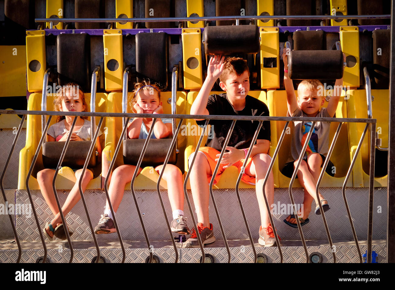 Quatre enfants attendent le début d'une ride sideshow à un country fair Banque D'Images