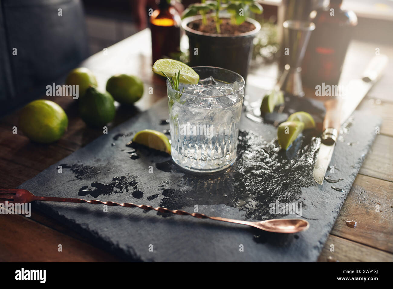 Close up d'un verre de gin tonic fraîchement préparé avec des tranches de citron et la cuillère sur le comptoir. Banque D'Images