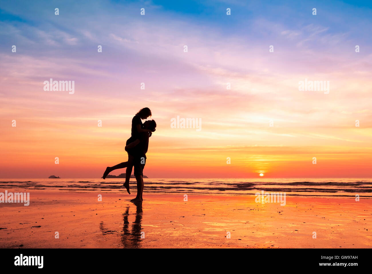 Couple sur la plage avec un beau coucher de soleil en arrière-plan, la levée de l'homme femme Banque D'Images