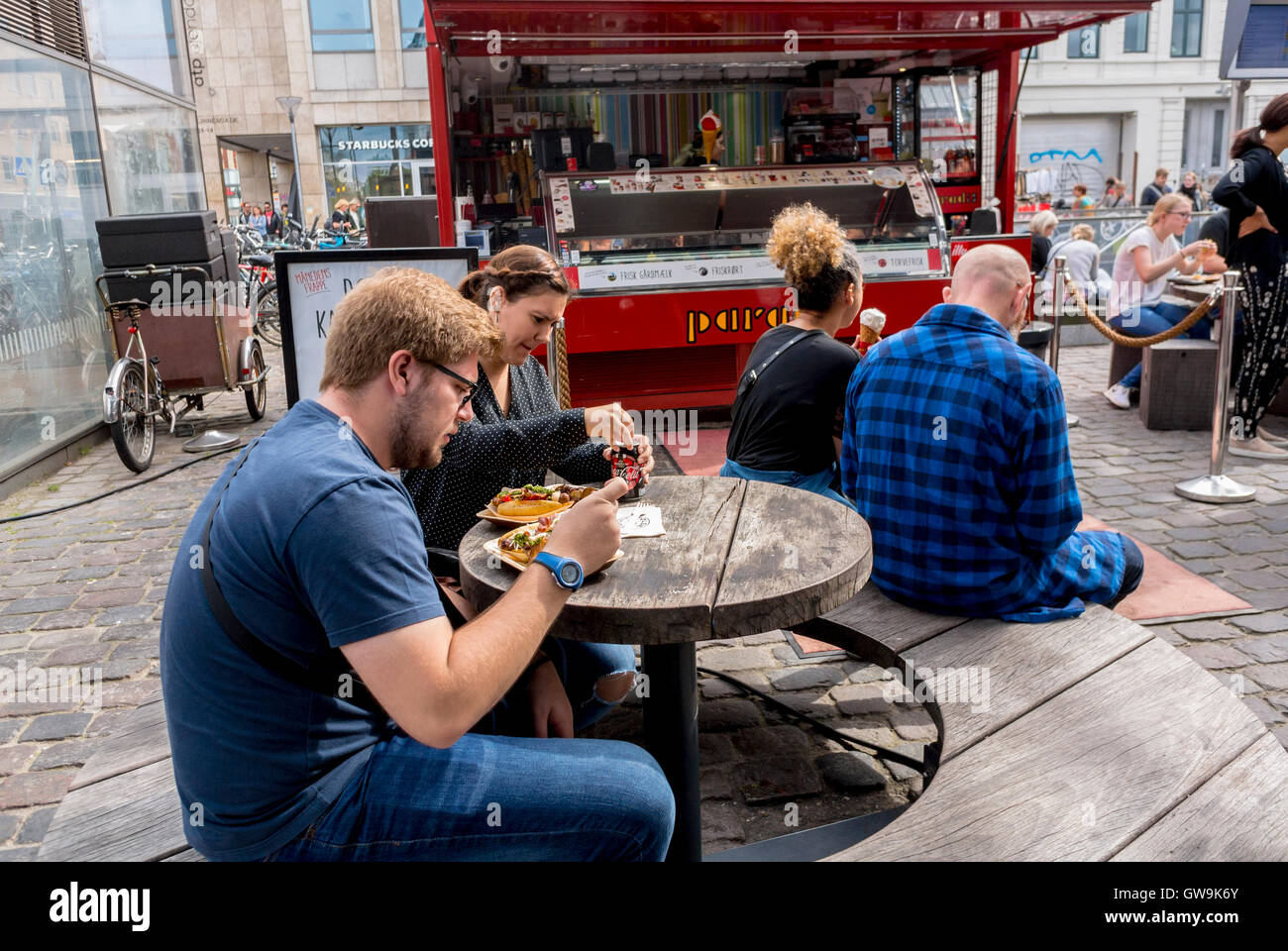 Copenhague, Danemark, café des scènes, les gens le partage des repas, de l'alimentation de rue, vendeurs, dans Torvfhallerne marché alimentaire, les quartiers locaux Banque D'Images
