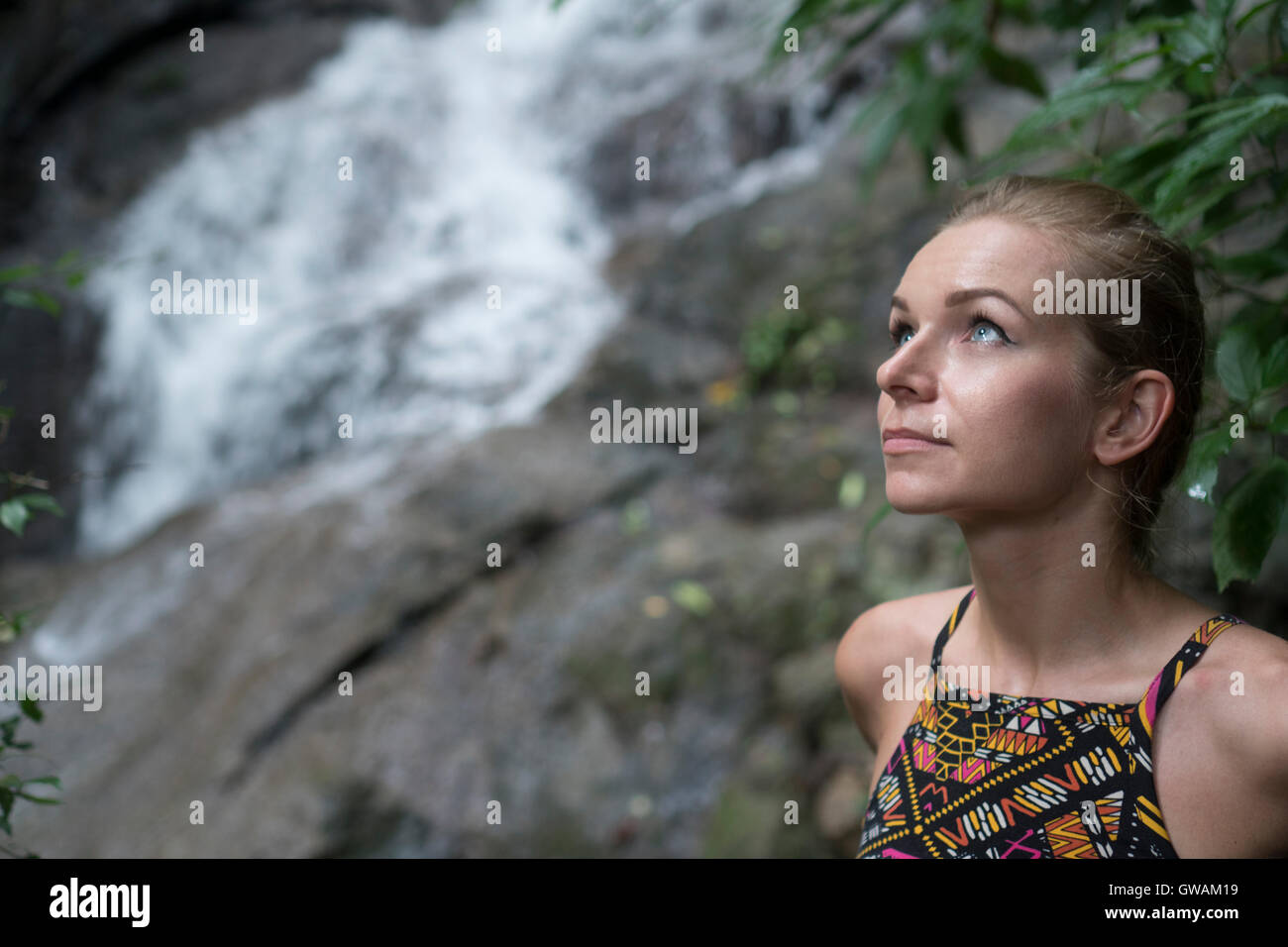 Face closeup de jolie blonde woman looking up sur cascade floue Banque D'Images