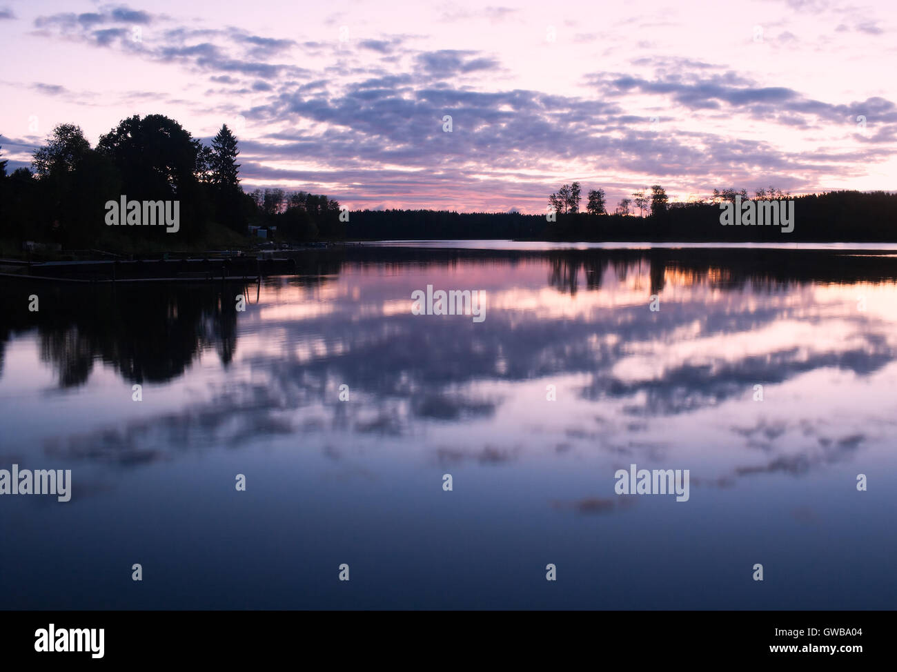 Paysage au petit matin avec surface de l'eau (avec les réflexions) et de la forêt, le lever du soleil, ciel et nuages. Banque D'Images