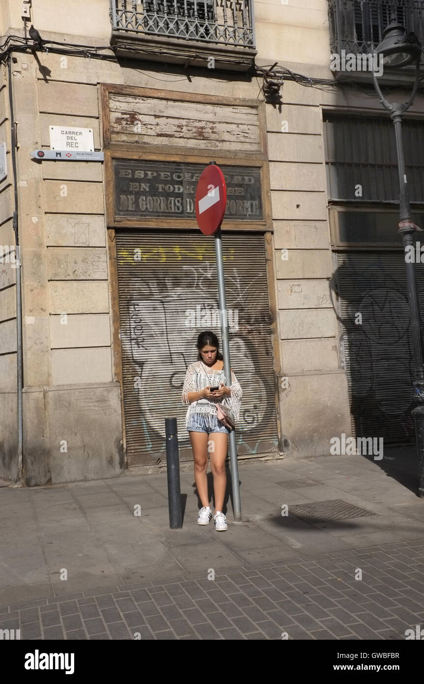Une jeune femme debout sur une rue de Barcelone à l'aide de son téléphone. Banque D'Images