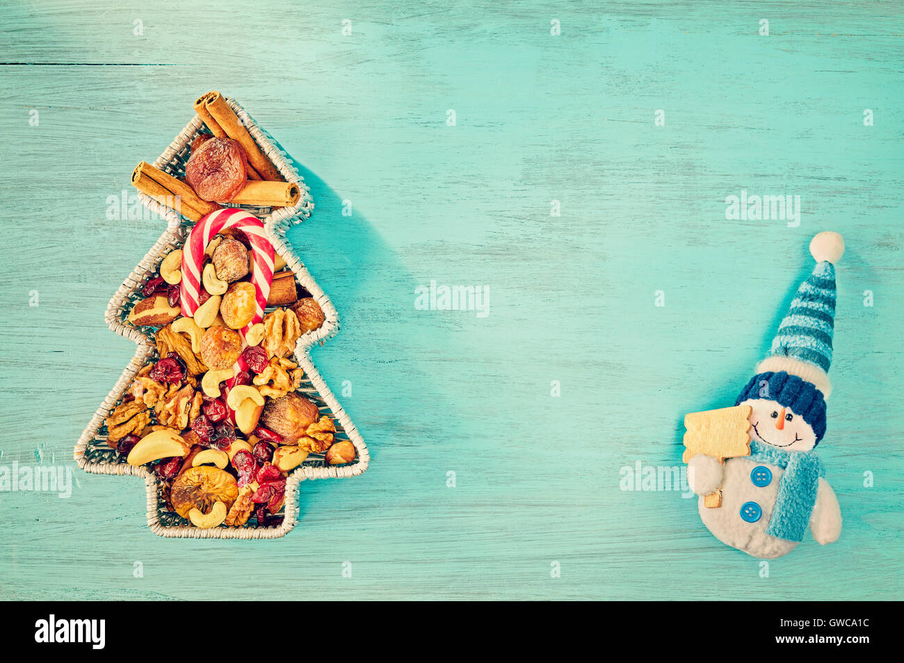 Retro jouet bonhomme stylisé en forme d'arbres de Noël et récipient rempli de fruits secs sur une table en bois rustique, top v Banque D'Images