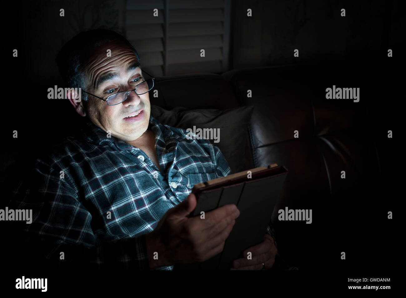 Middle aged man wearing pajamas Tablette de lecture la nuit au lit à la peur ou surprise with copy space Banque D'Images